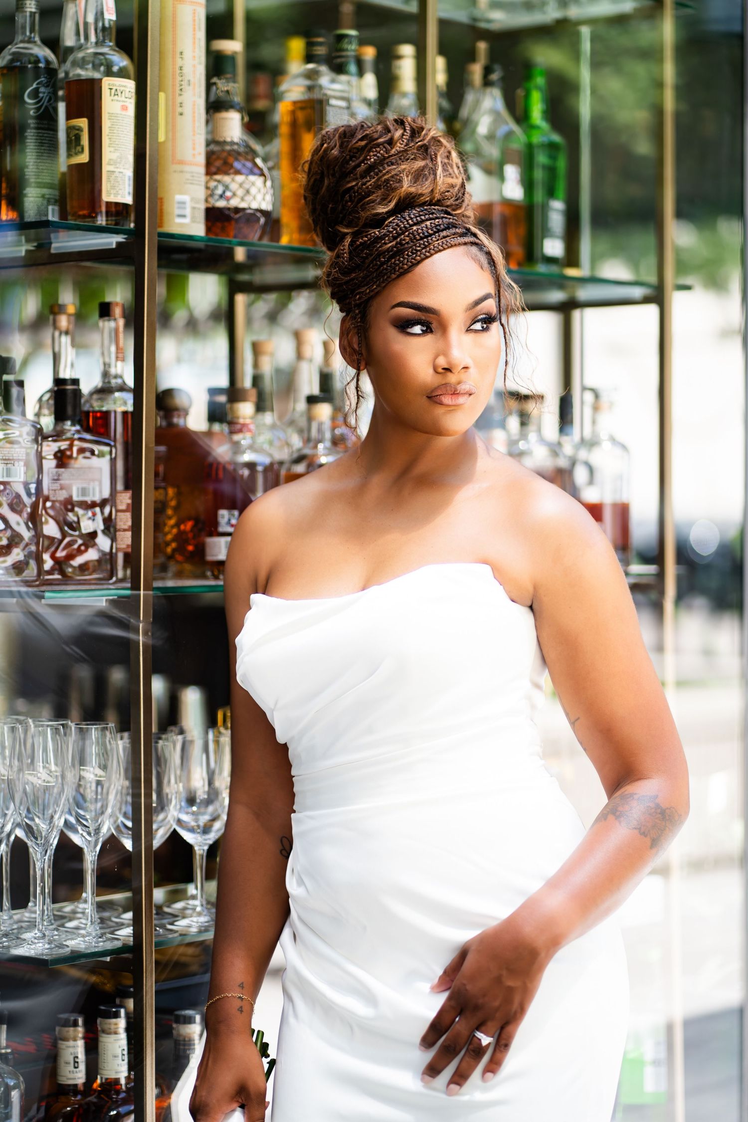 Elegant bridal portrait against a glass display case in a white gown.