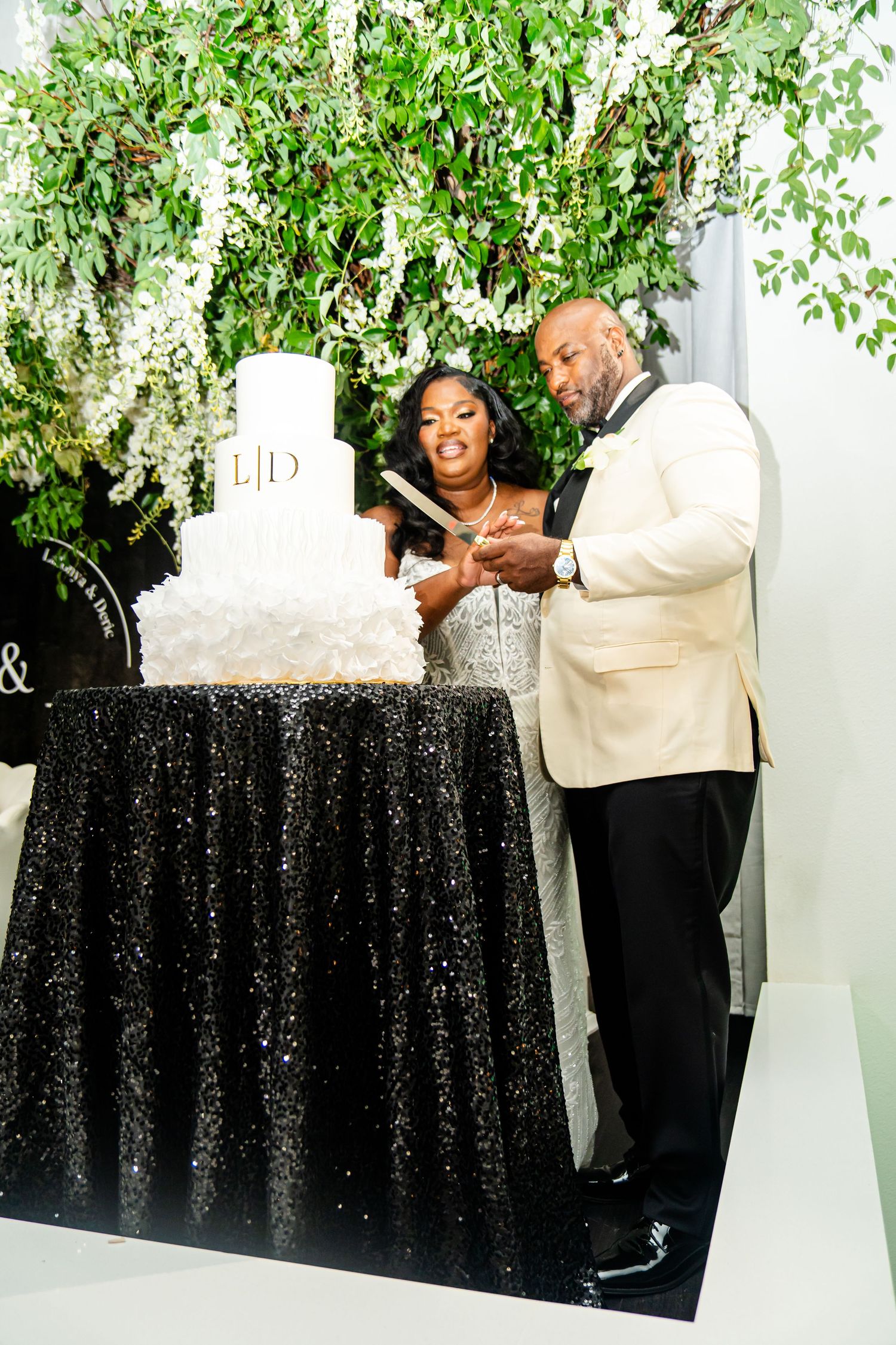 Wedding decor featuring black sequin tablecloths and hanging greenery.