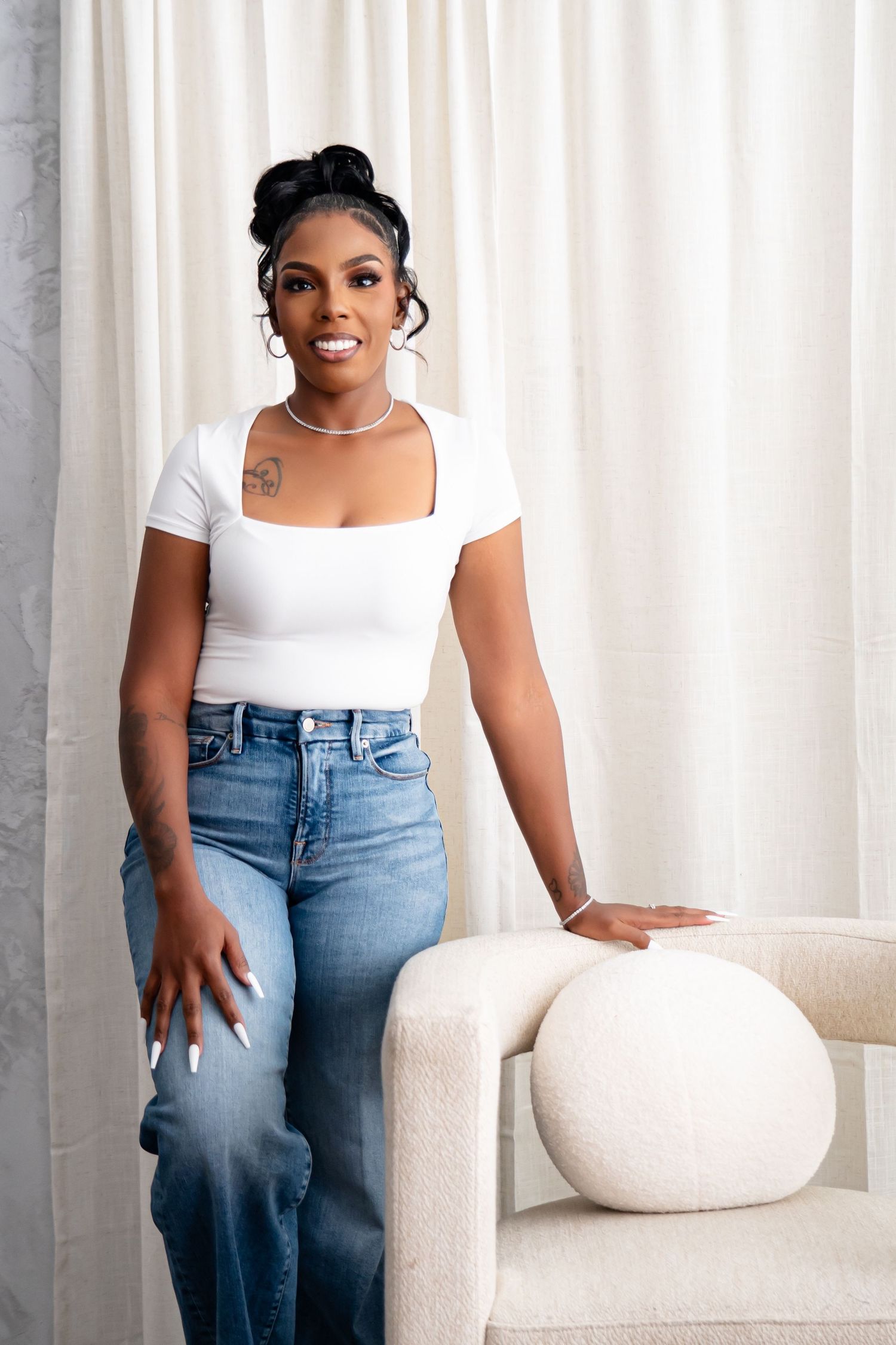 Modern portrait session on white couch with minimalist curtain backdrop.