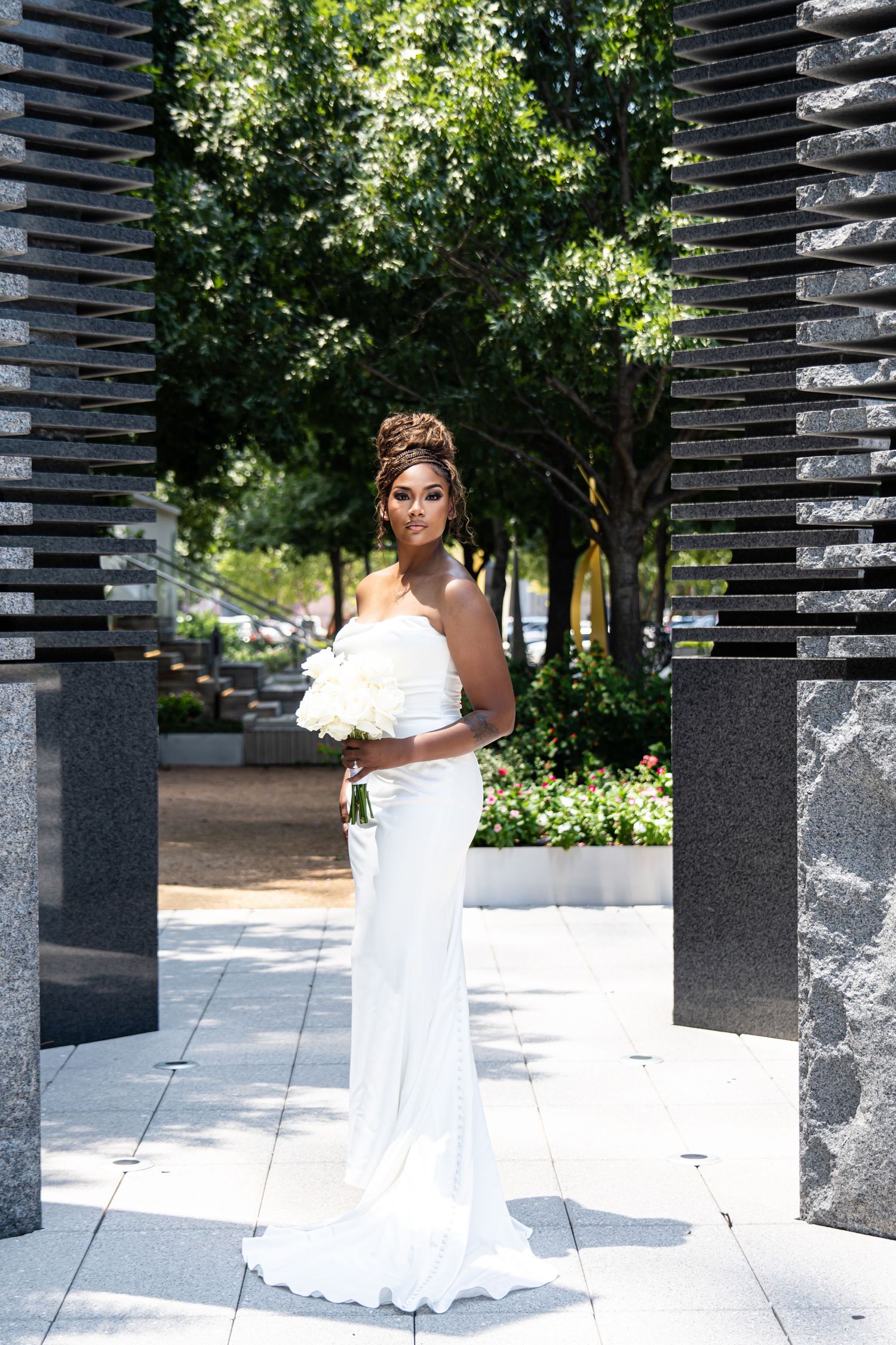 Bridal portrait session among modern architectural columns in outdoor urban setting.