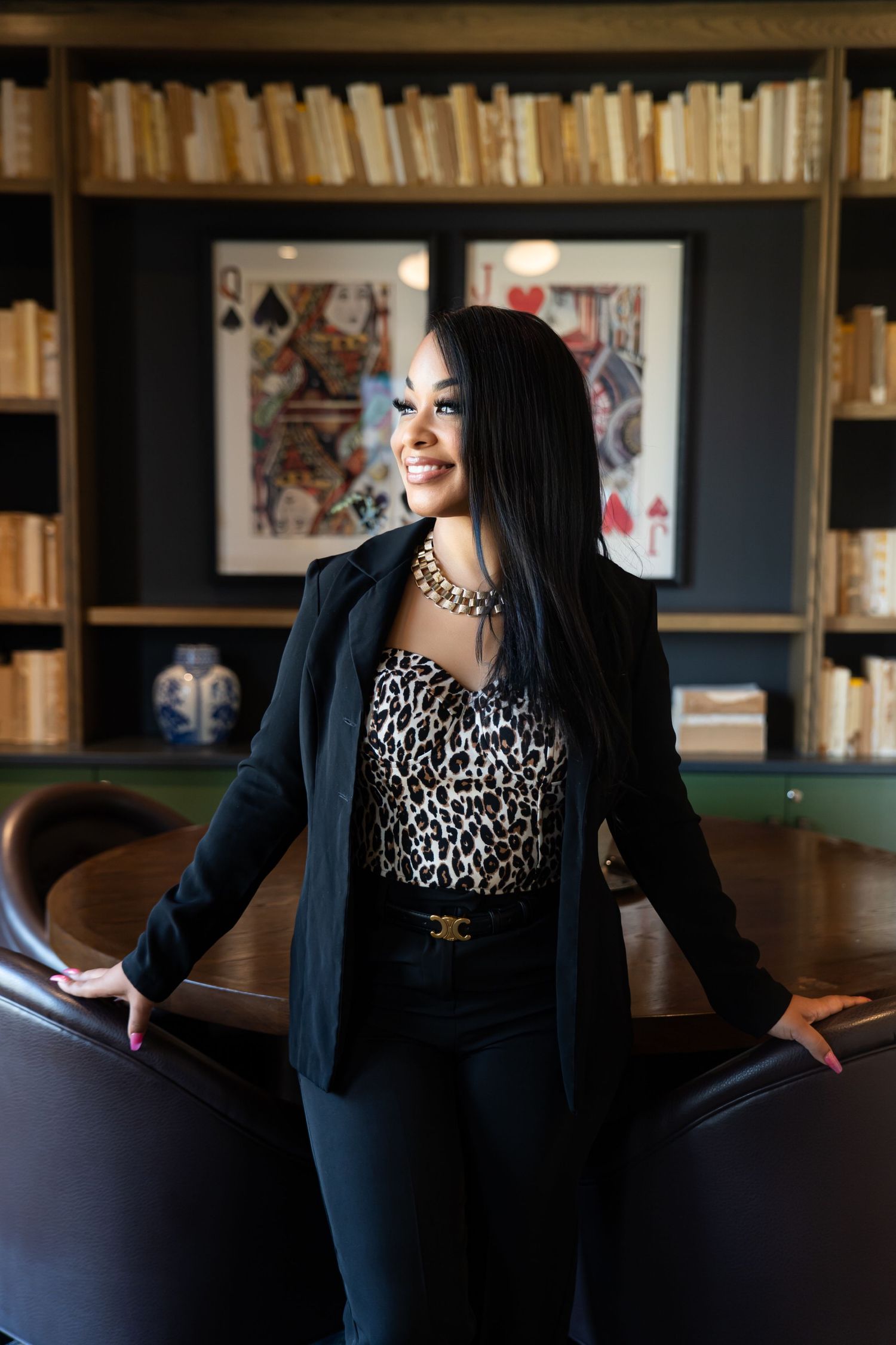 Elegant business portrait featuring a black blazer and leopard print top in a library setting.