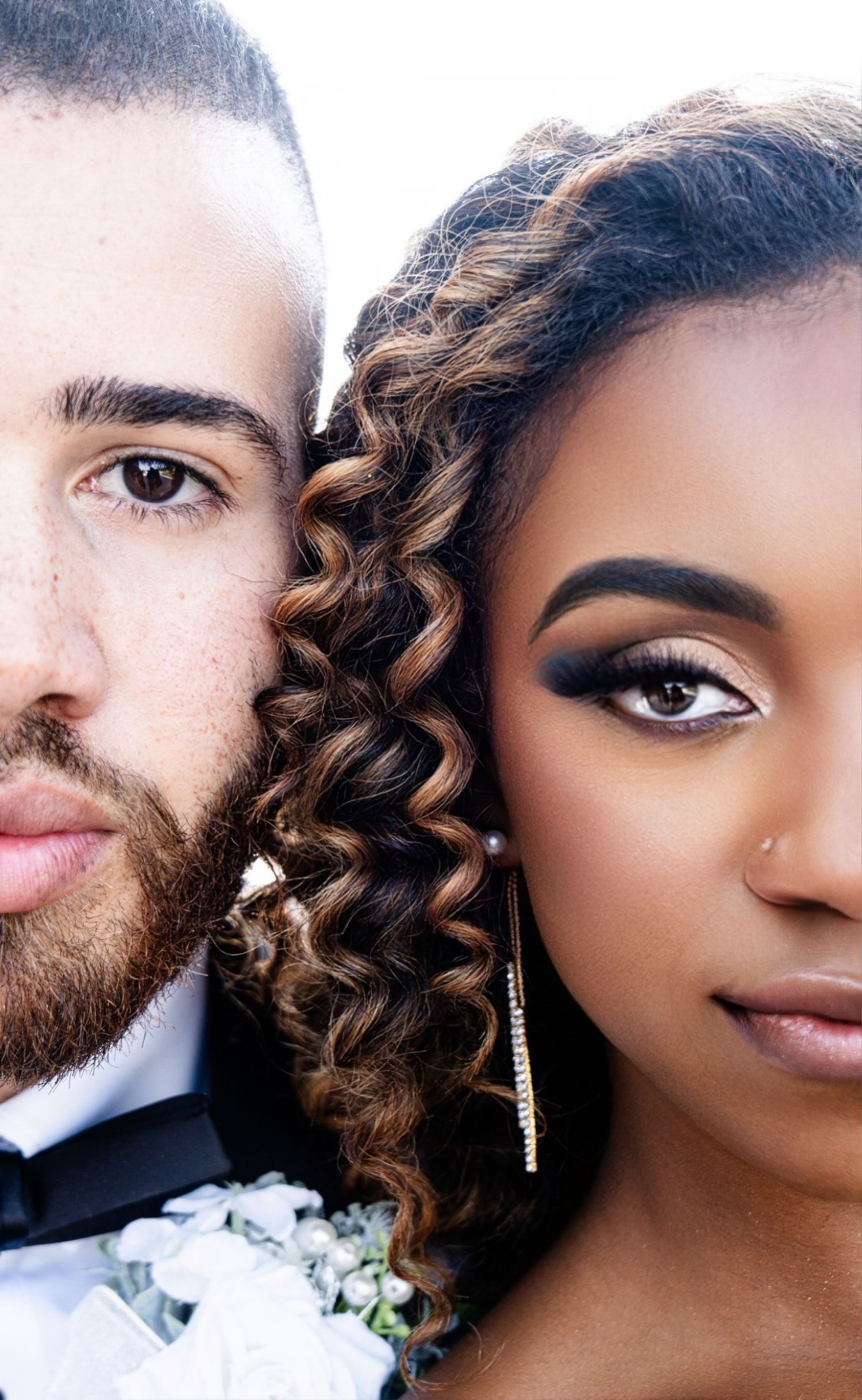 Close-up portrait of a couple in wedding attire with beautiful curly hair and elegant makeup.
