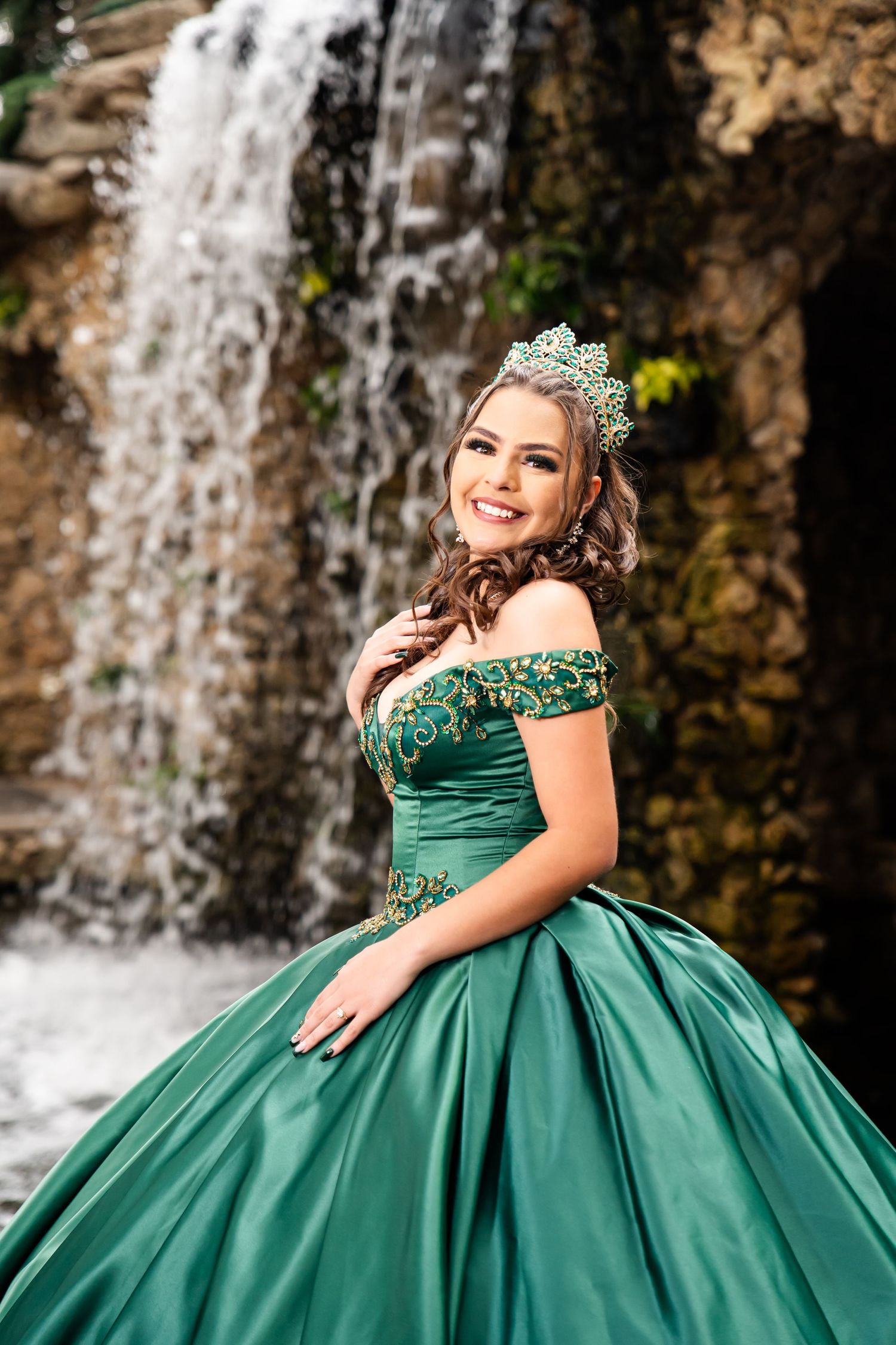 Beautiful emerald ball gown with detailed beadwork photographed near a cascading waterfall.