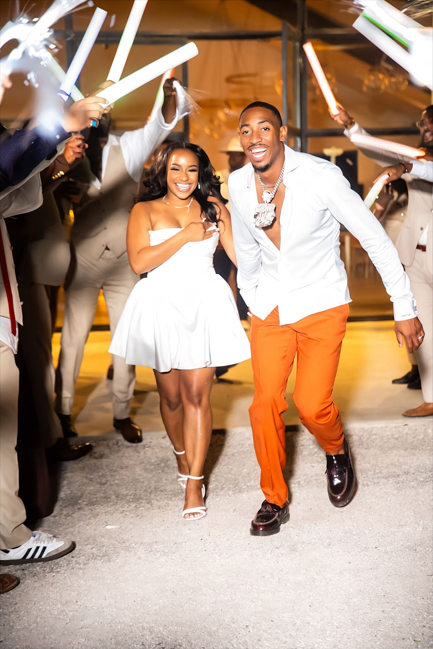 A couple runs through a sparkler exit tunnel during wedding celebrations.