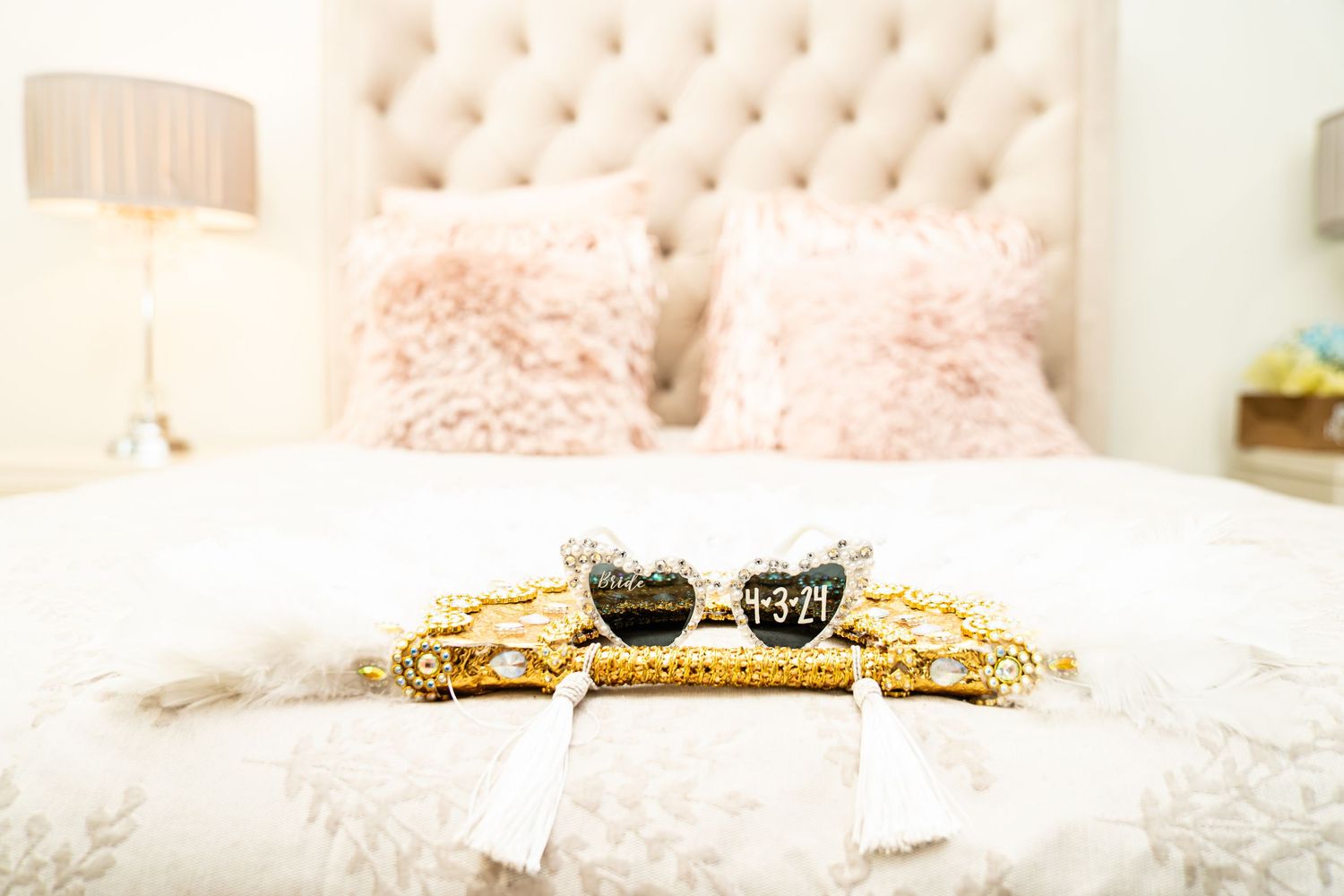 Wedding accessories and jewelry displayed on a light pink bedspread.