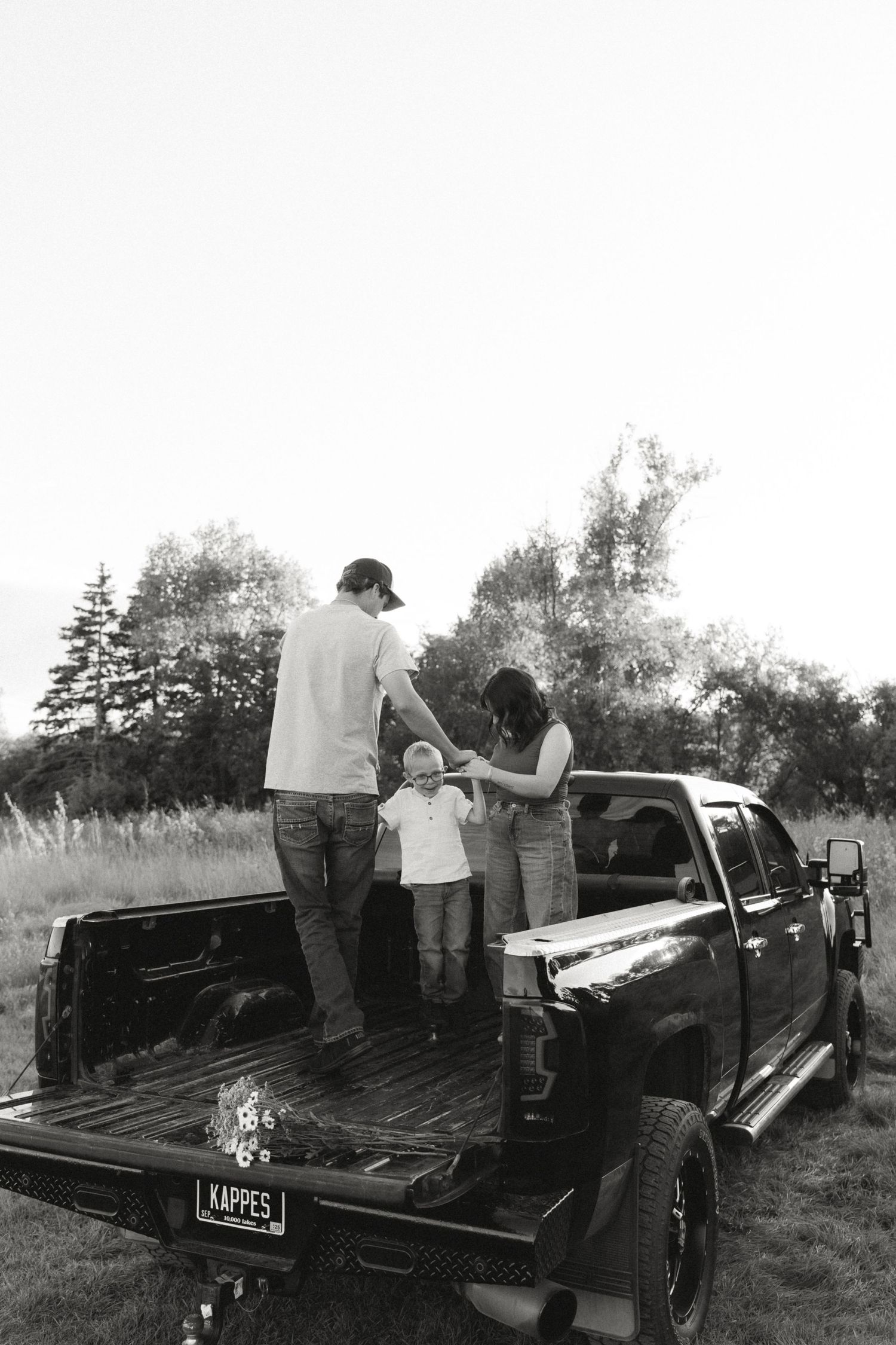People loading items into the back of a black pickup truck in an outdoor setting.