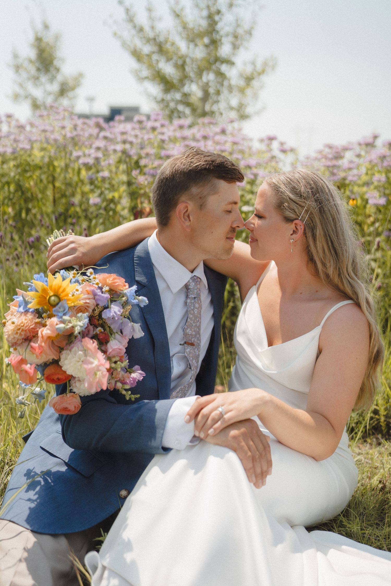 A romantic wedding photoshoot series showing a couple in a navy suit and white dress embracing outdoors with floral bouquets.