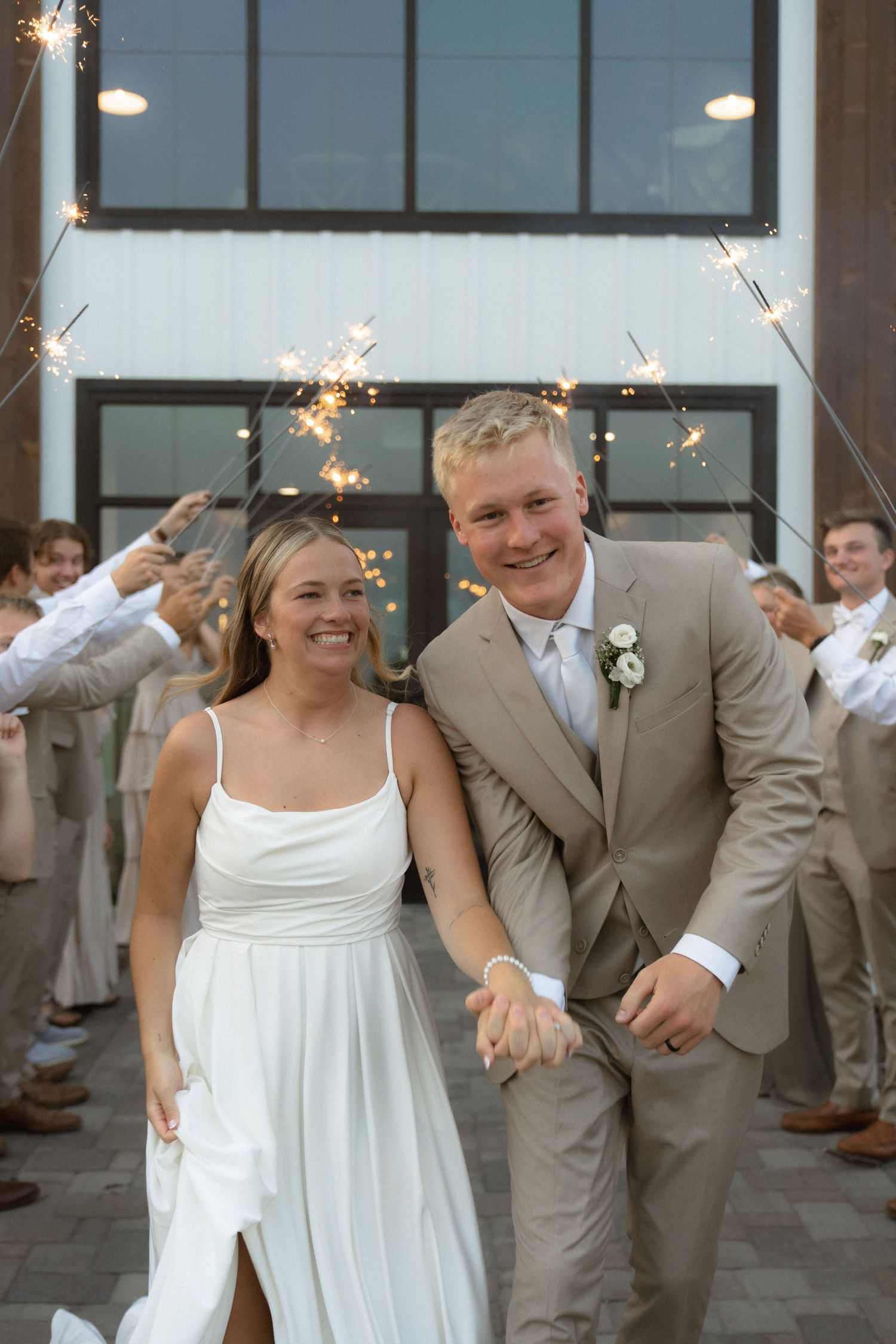 Newlyweds exit their wedding celebration through a tunnel of sparklers held by guests.