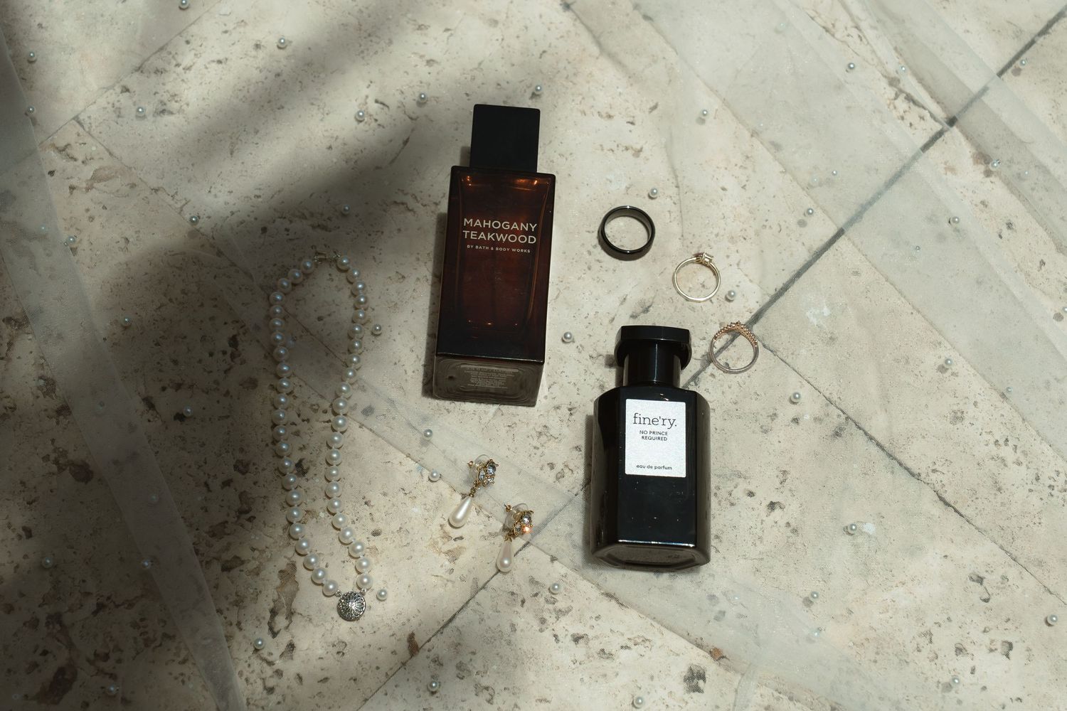 Perfume bottles arranged on a textured concrete or marble surface with shadows and reflections.
