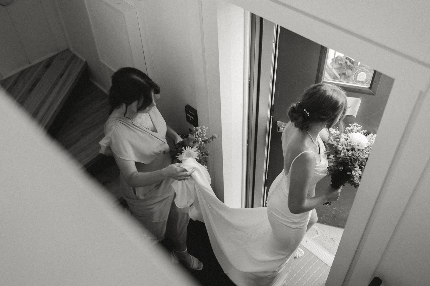 A black and white photo captures wedding preparation moments in a mirror reflection.