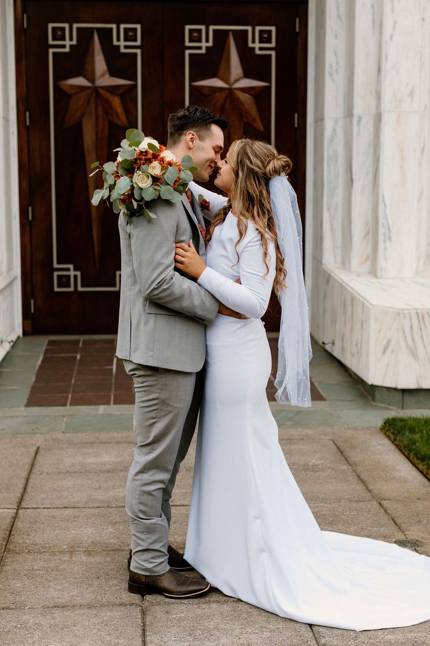 Wedding couple shares intimate first look moment outside church entrance.