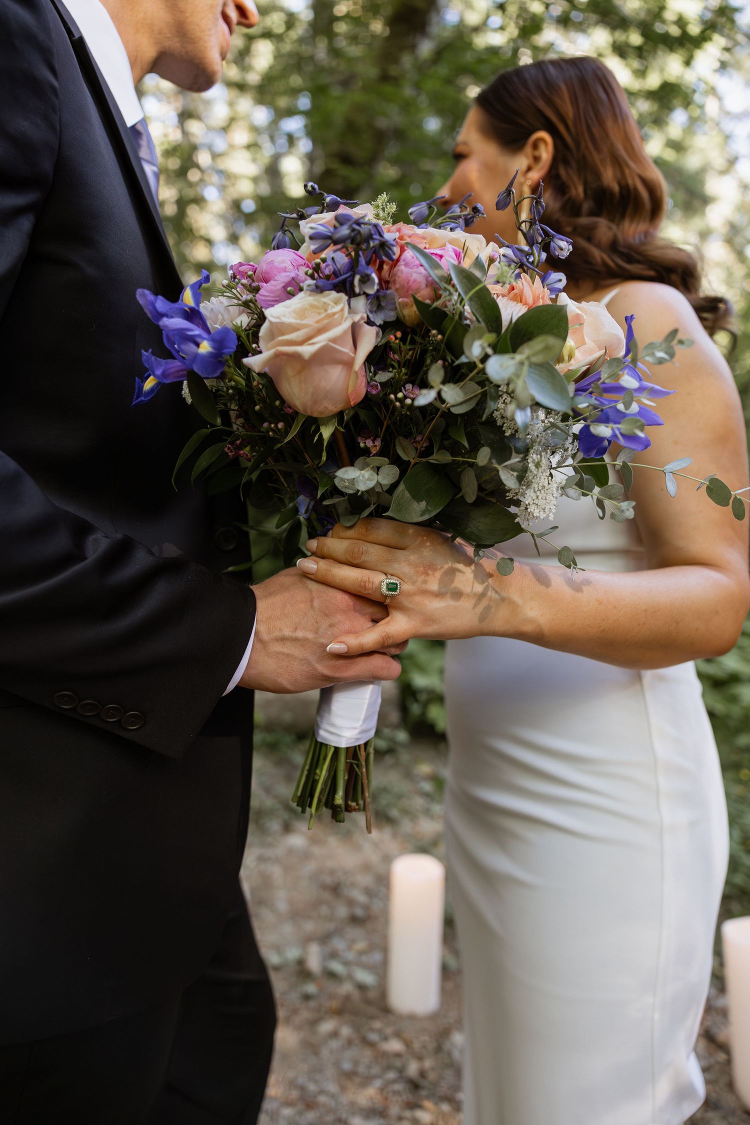 Close-up shots of wedding couple exchanging bouquet during outdoor ceremony with white and purple flowers.