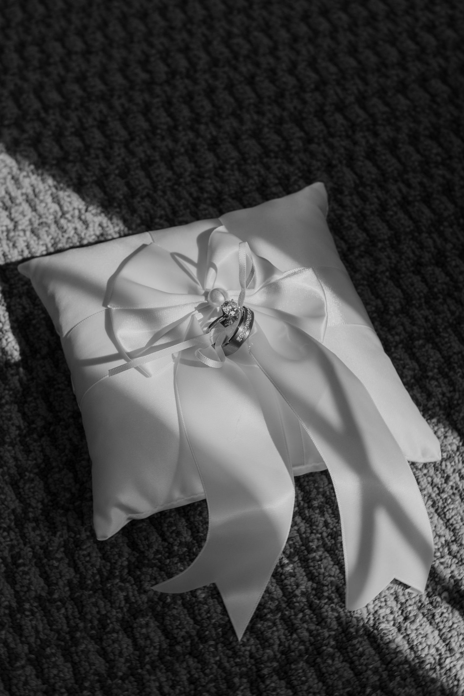 A sequence of black and white photographs showing a white satin bow from different angles on a dark textured background.