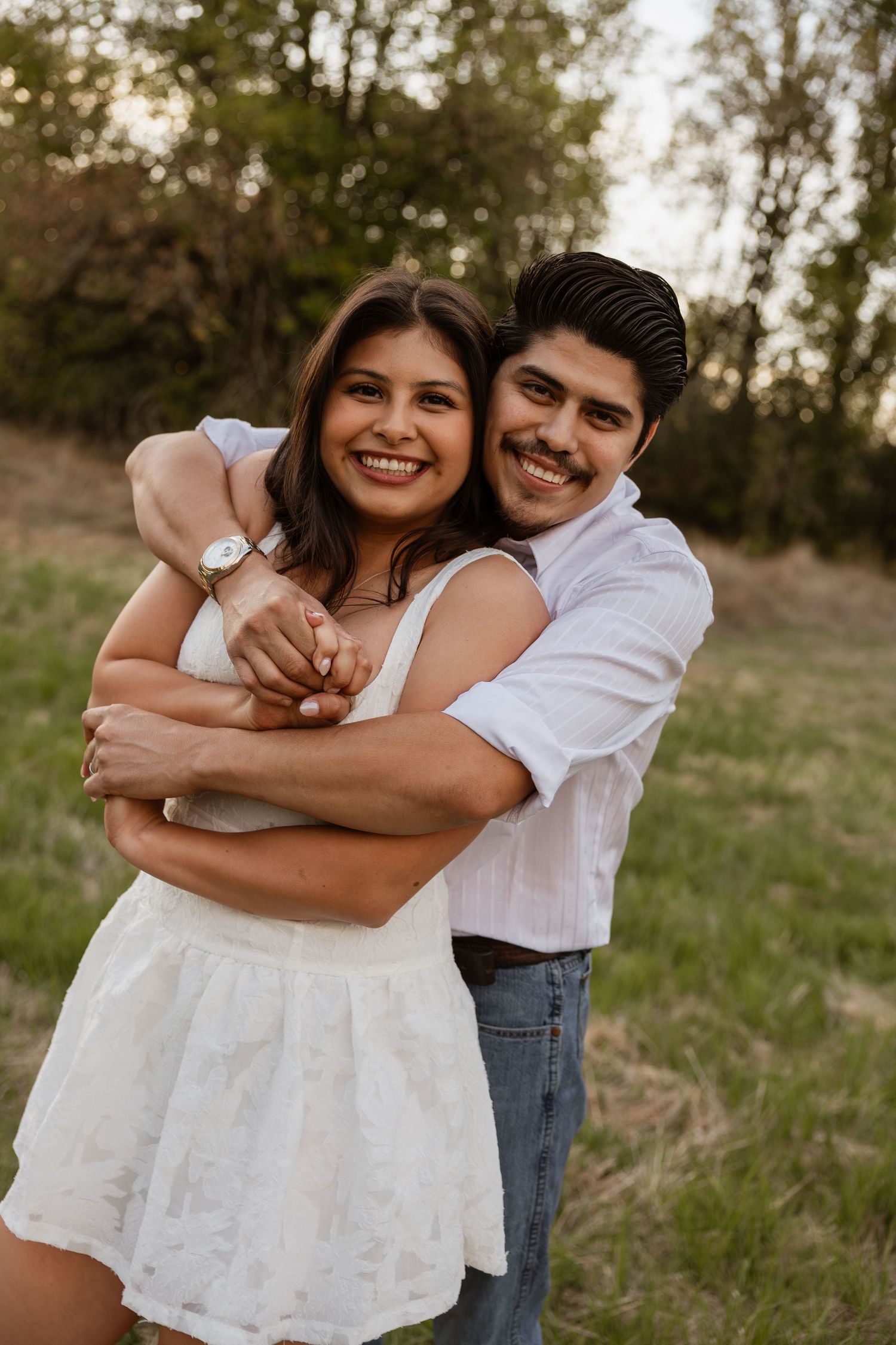 Couple in white outfits sharing joyful embraces during outdoor photo session.