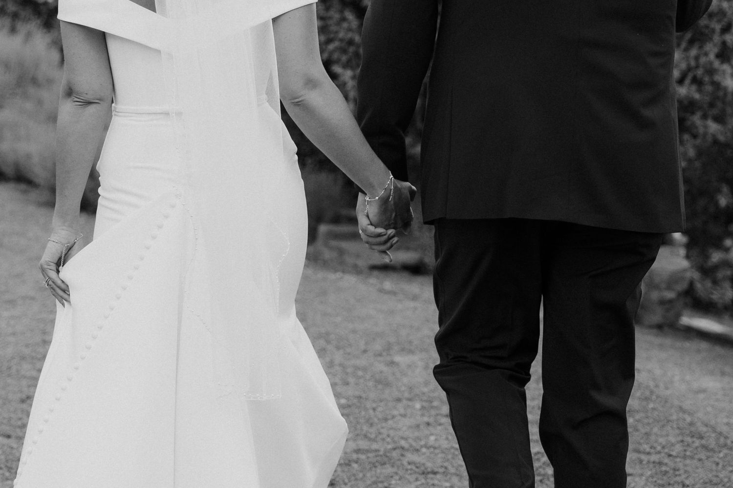 Candid black and white photo of wedding guests gathered outdoors during a ceremony.