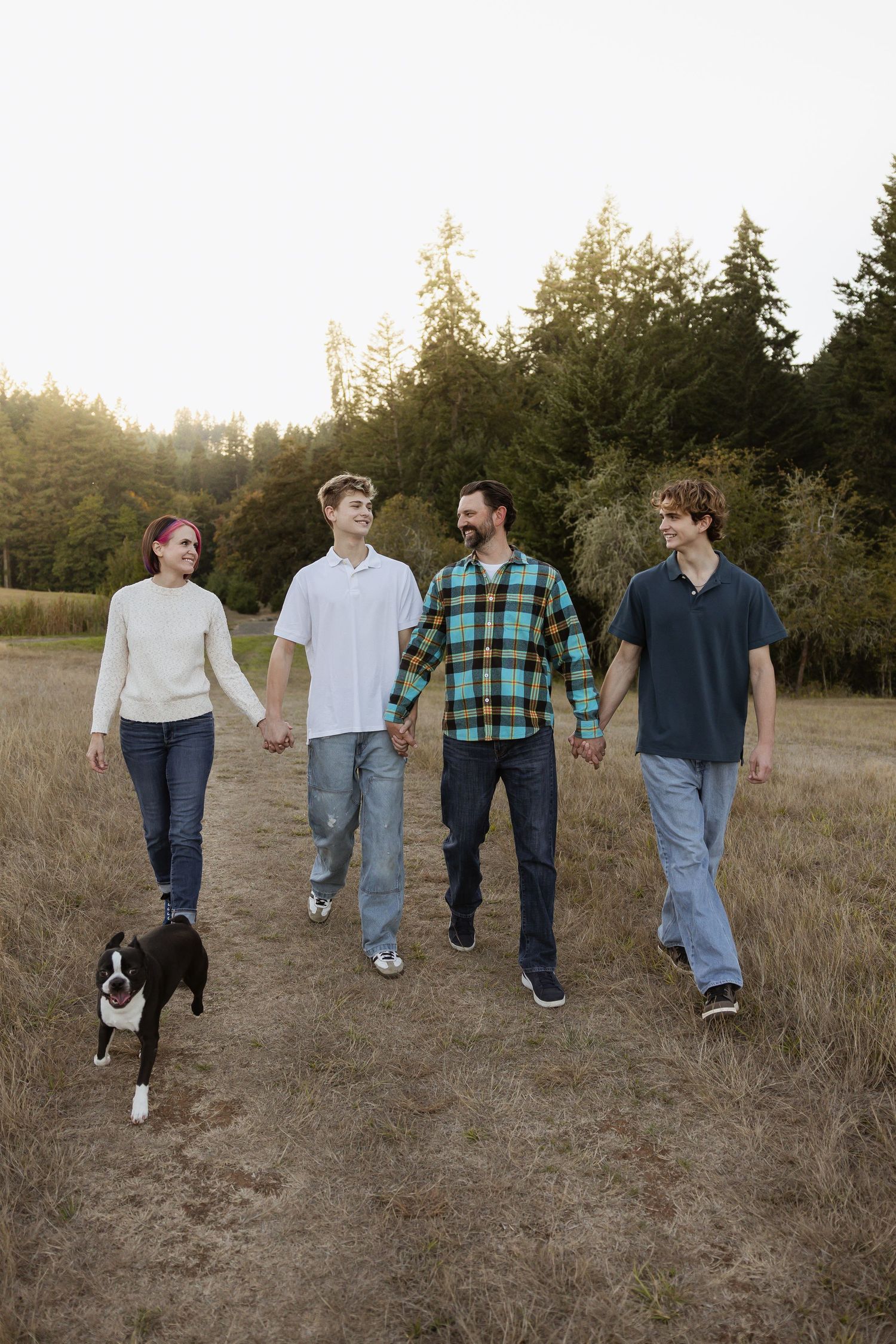 Group of friends walking together through a grassy field at sunset in casual attire.