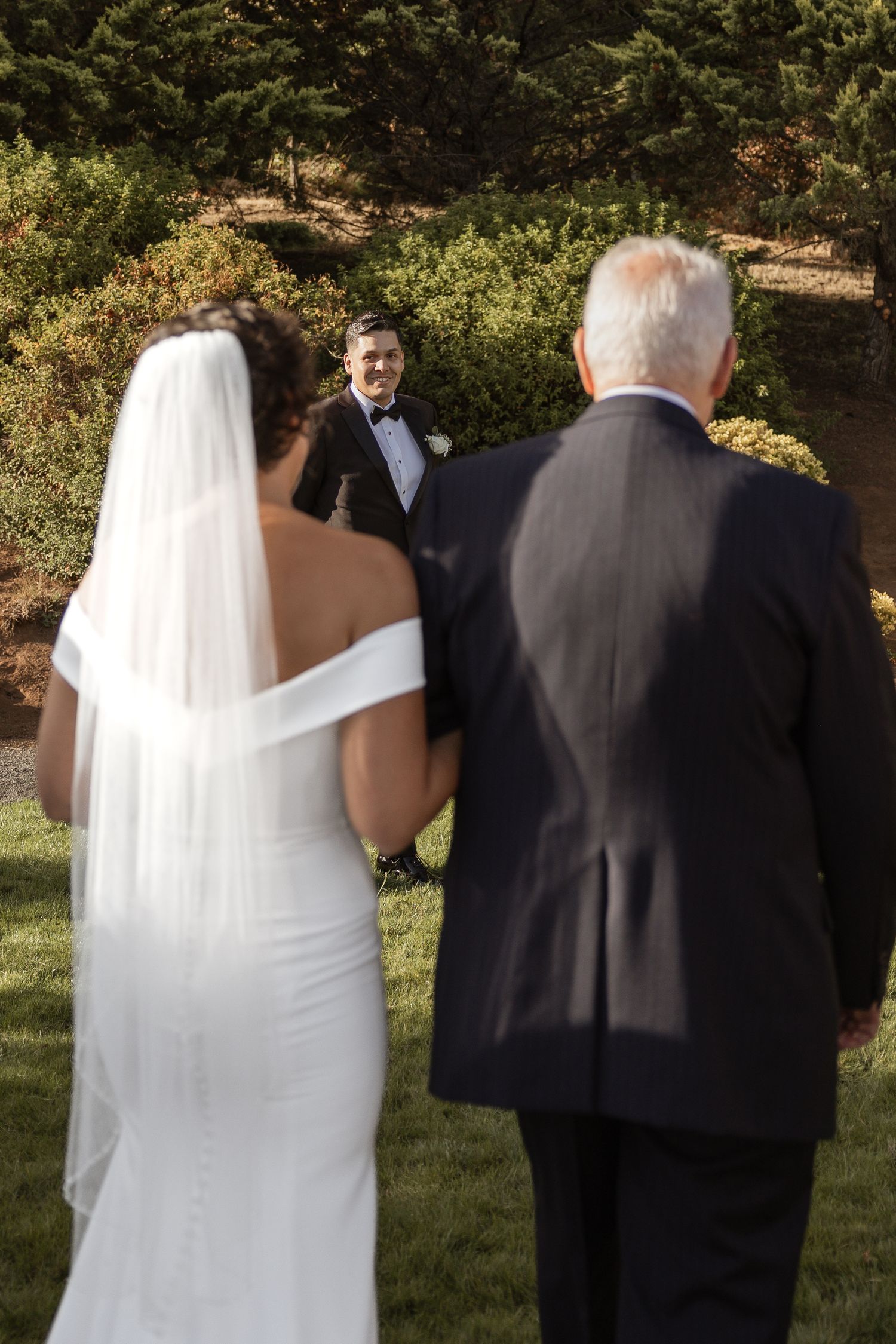 Wedding party walking through a garden setting during golden hour.