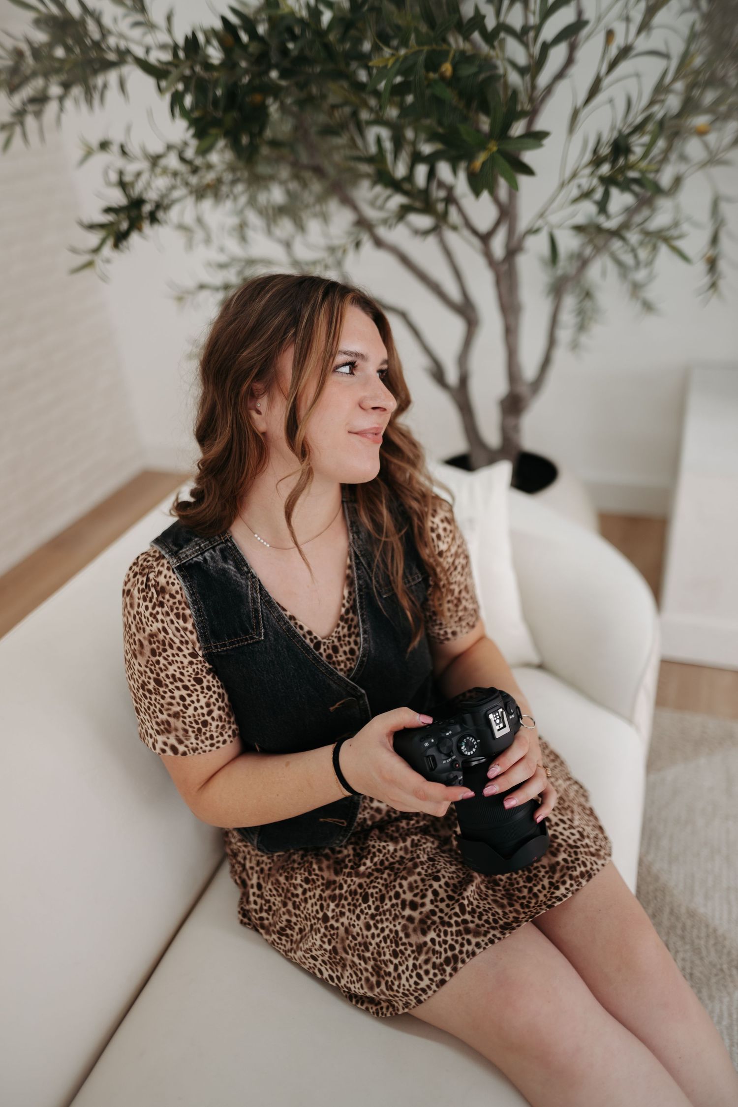 Woman in leopard print dress relaxing at home with indoor plants.