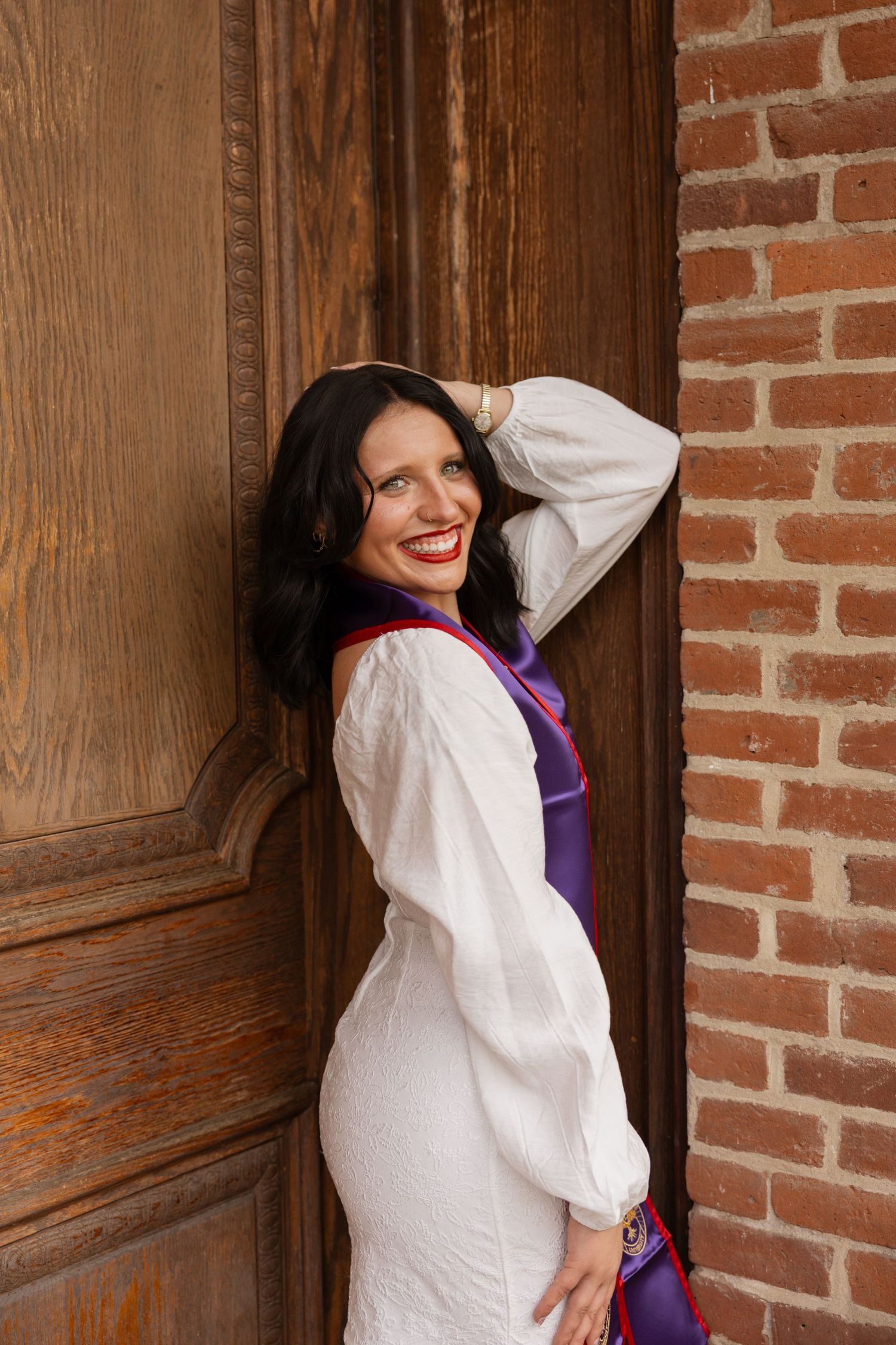 Person in white shirt poses playfully against rustic brick wall and wooden door in four sequential shots.
