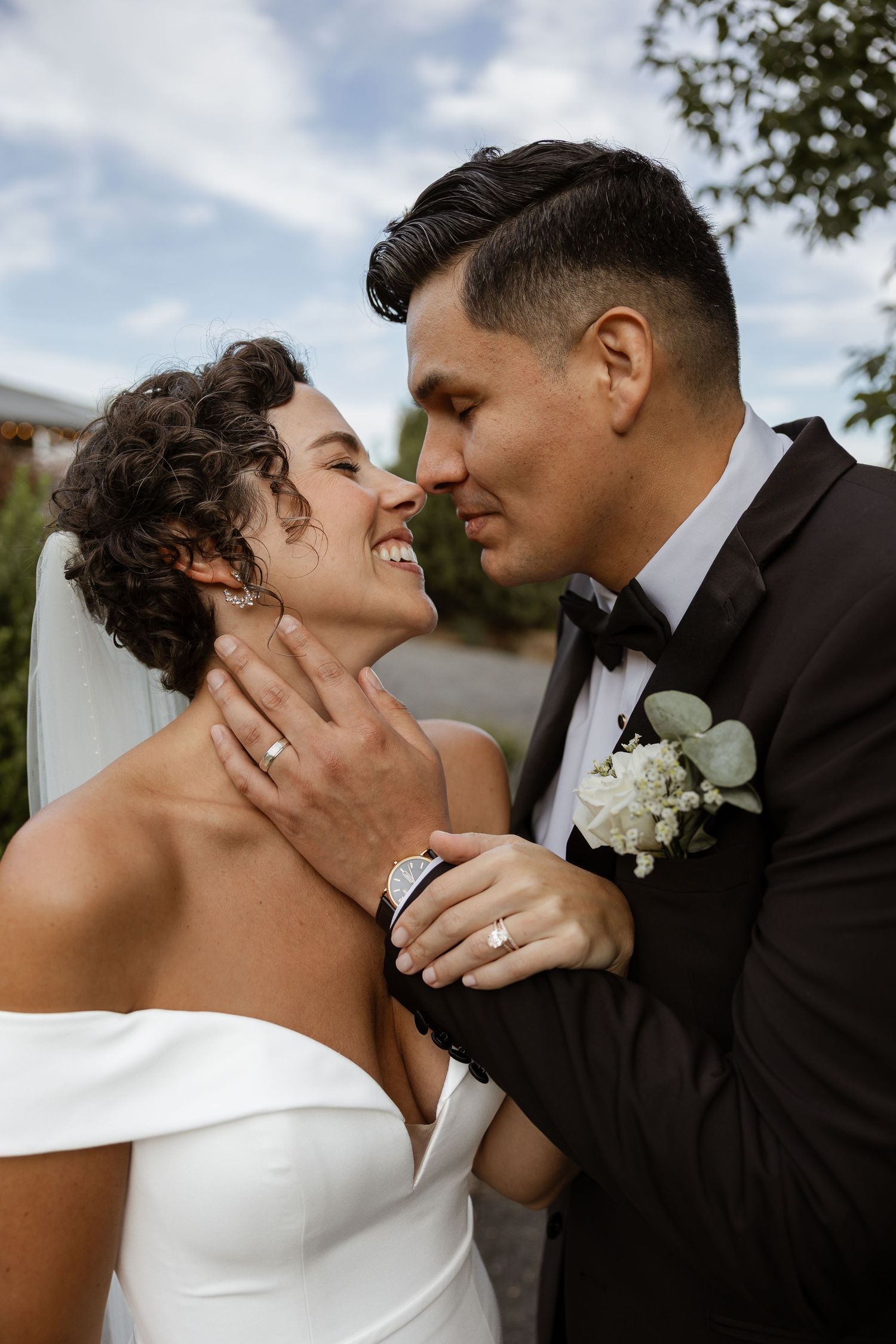 A romantic wedding portrait showing a tender moment between newlyweds wearing classic formal attire.