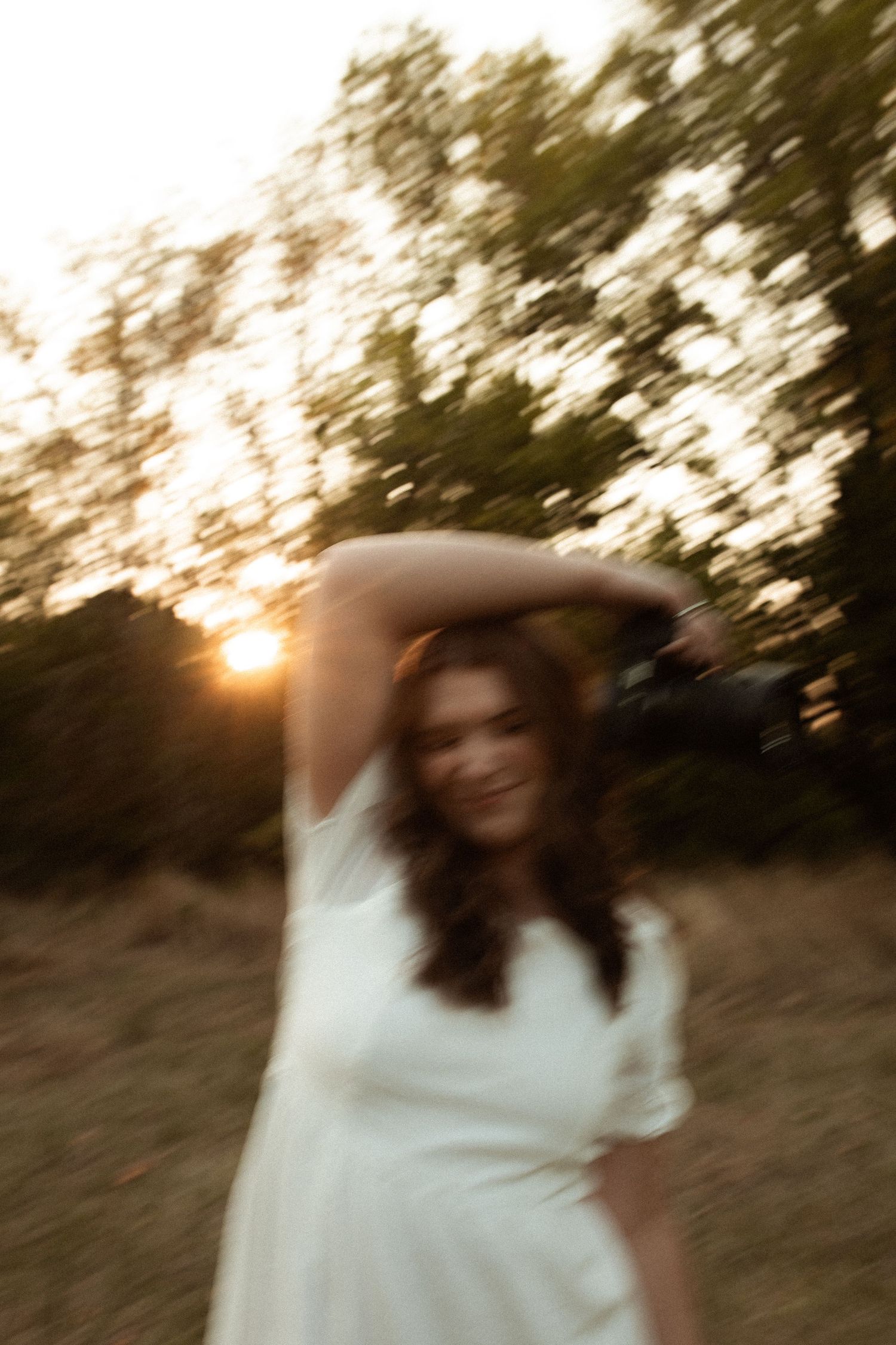 Artistic motion blur portrait of a bride in white dress at golden hour.
