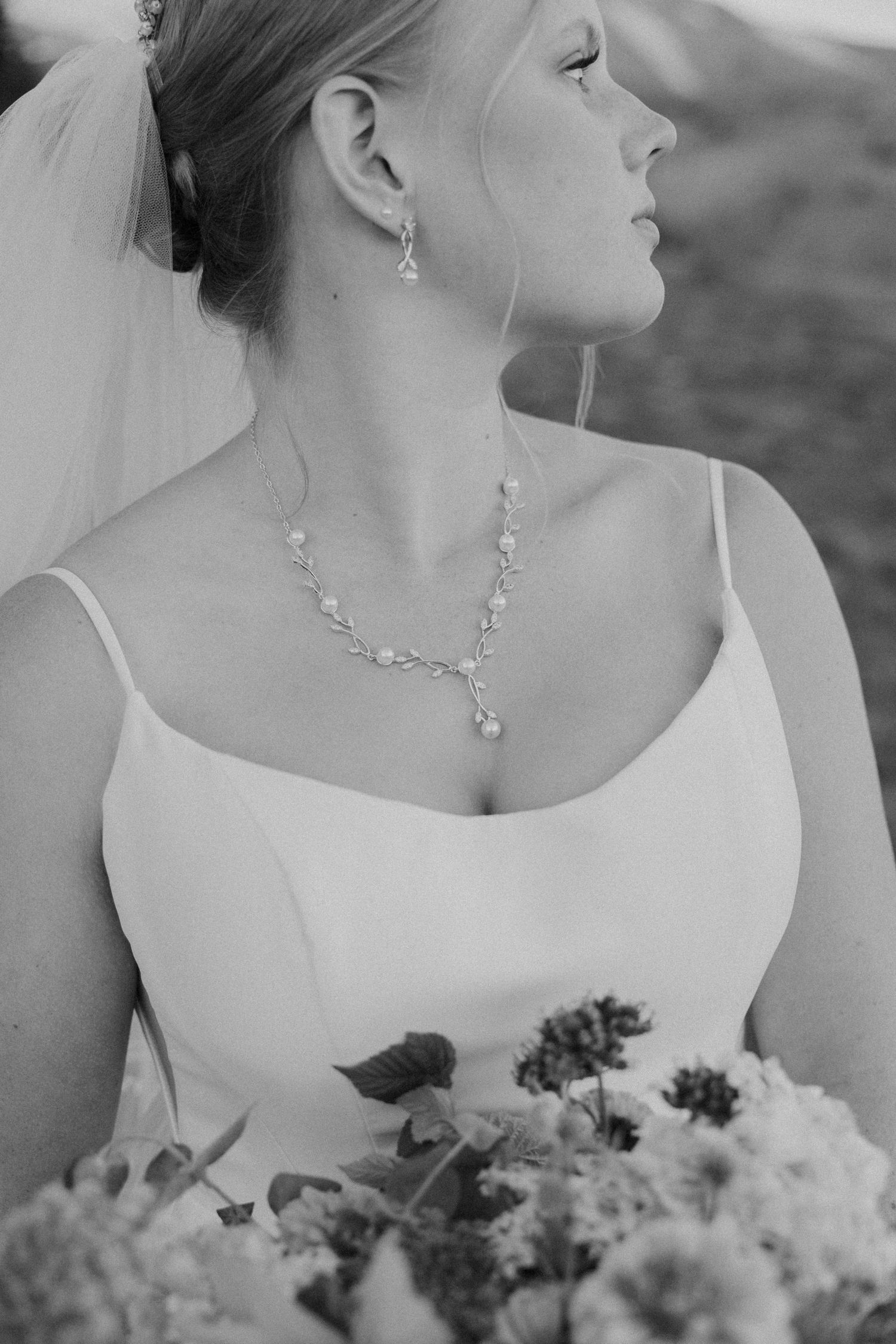 Elegant black and white close-up details of bridal jewelry and bouquet against a soft background.