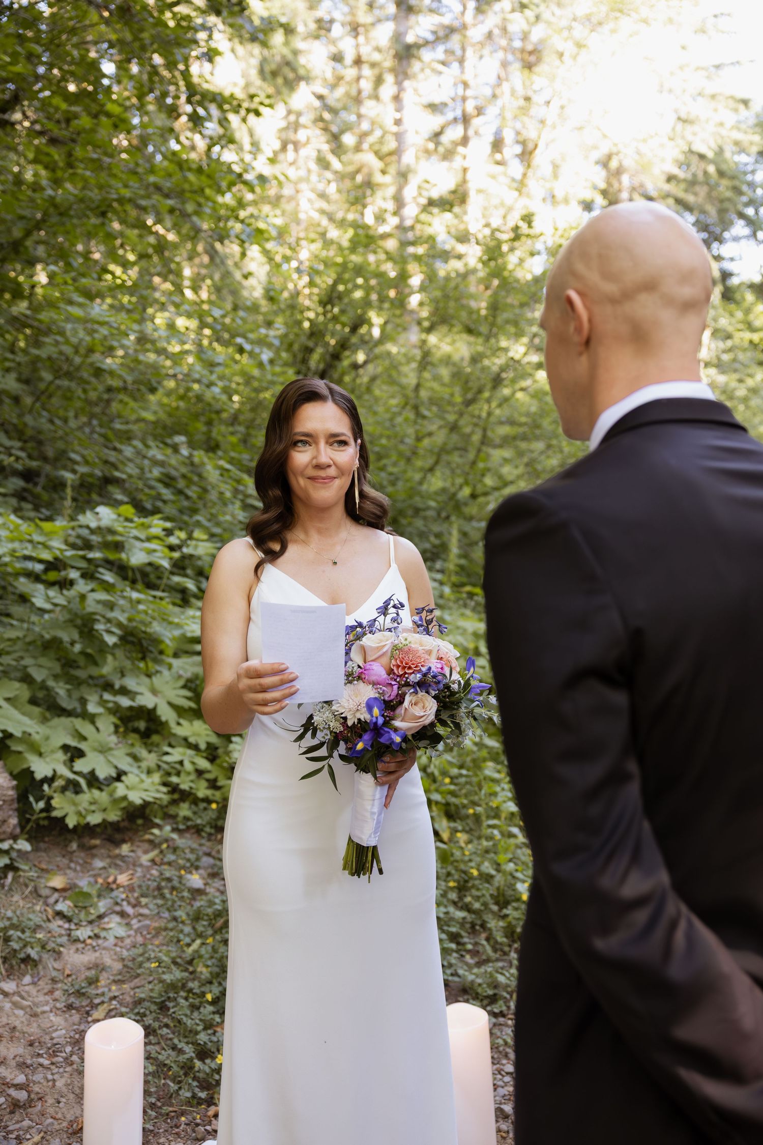 A couple shares an emotional first look moment in a lush forest setting during their outdoor wedding ceremony.