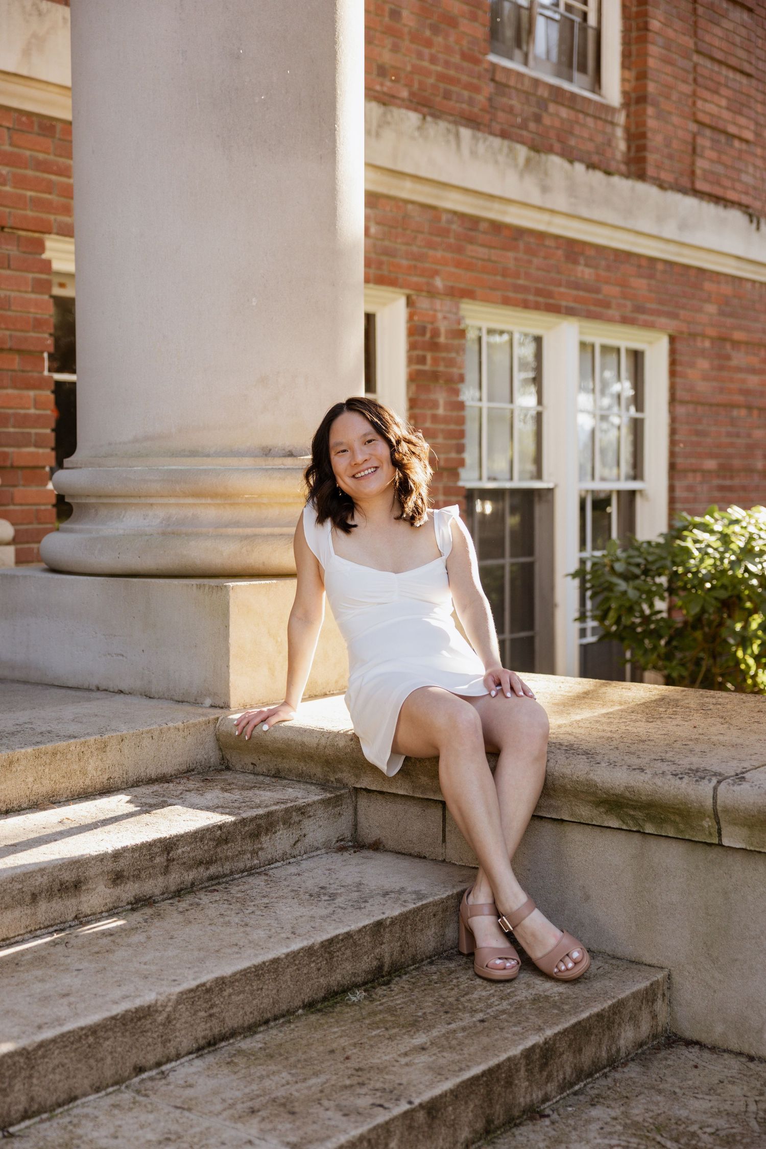 A series of photos showing someone in a white dress sitting on concrete steps outside a brick building in warm sunlight.