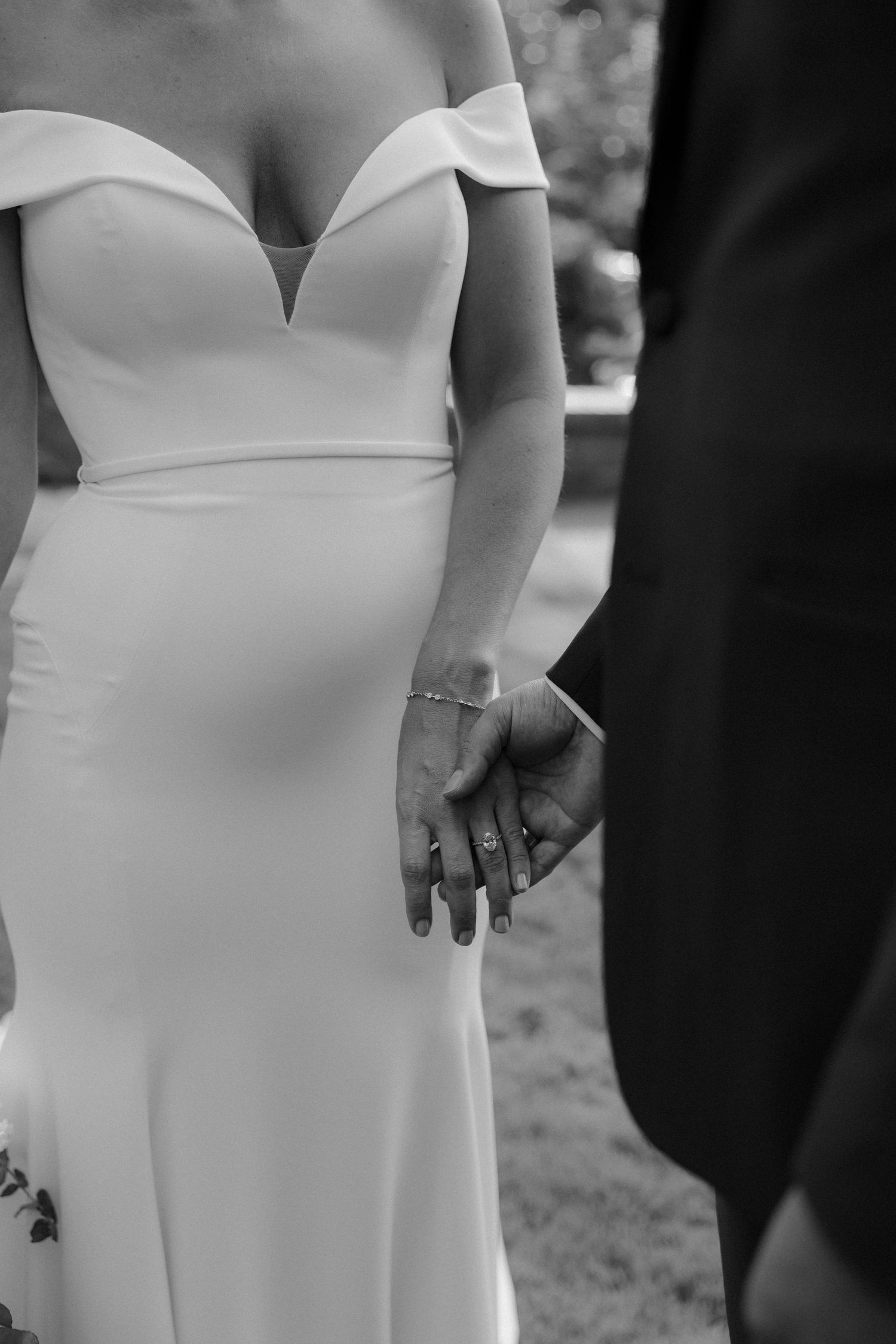 Close-up details of an elegant white wedding dress bodice with off-shoulder neckline and fitted silhouette.