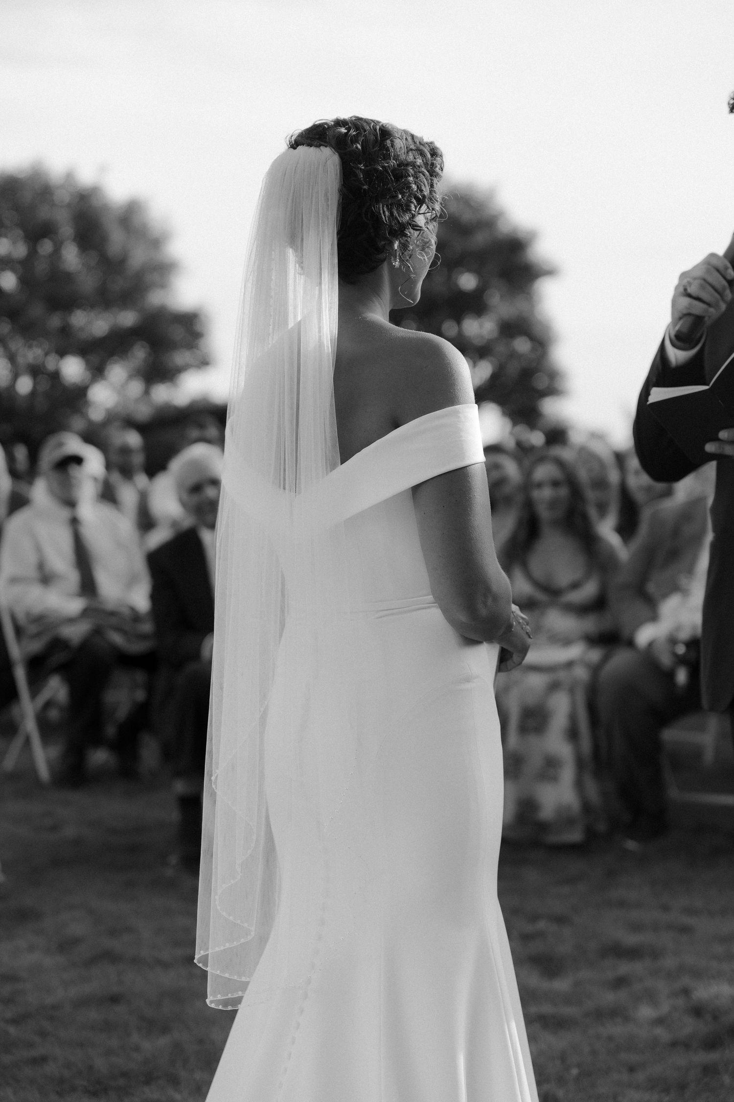 Black and white wedding ceremony photo capturing intimate moments outdoors.