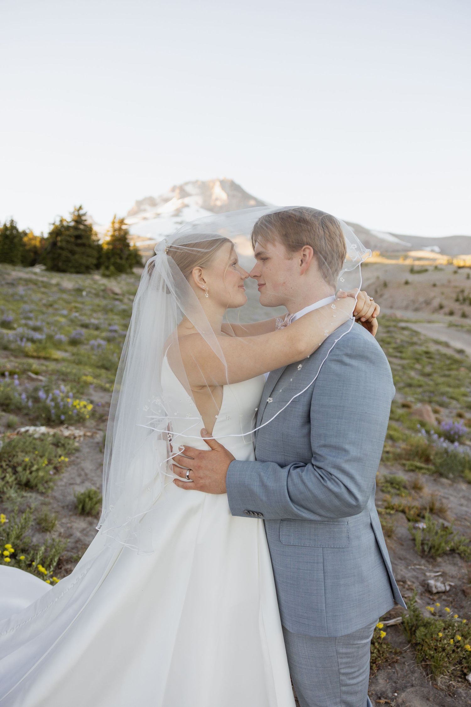A couple shares an intimate moment during their mountain wedding photoshoot at sunset.