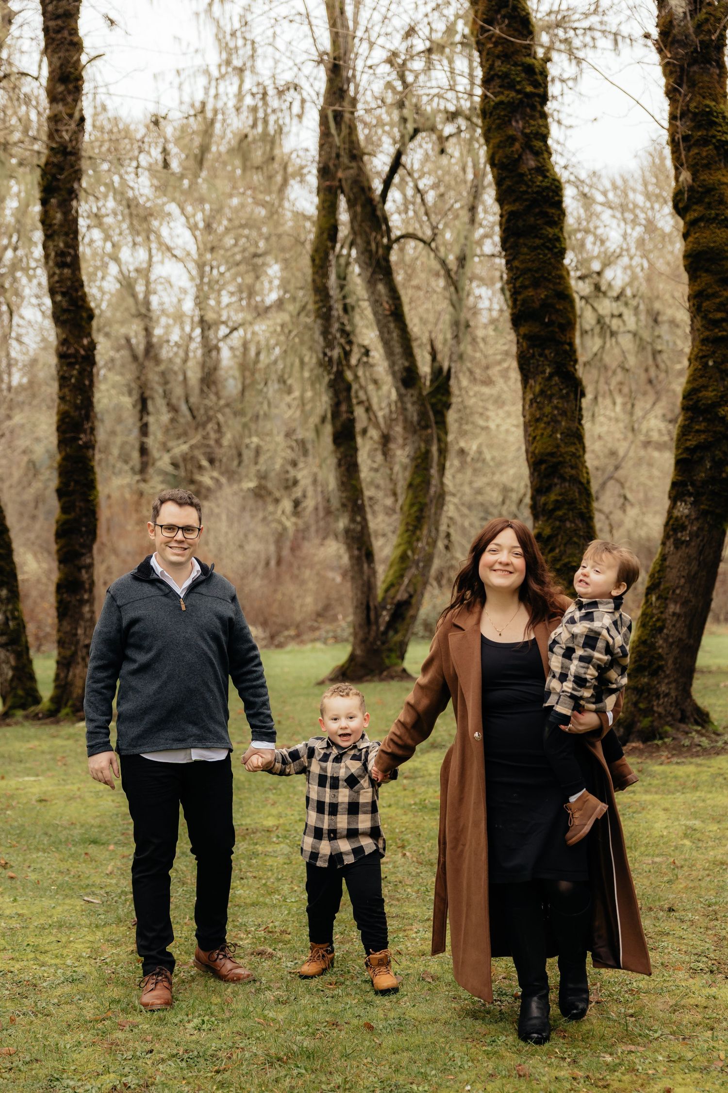 A series of candid family photos taken in a wooded area with bare trees and green grass in the background.