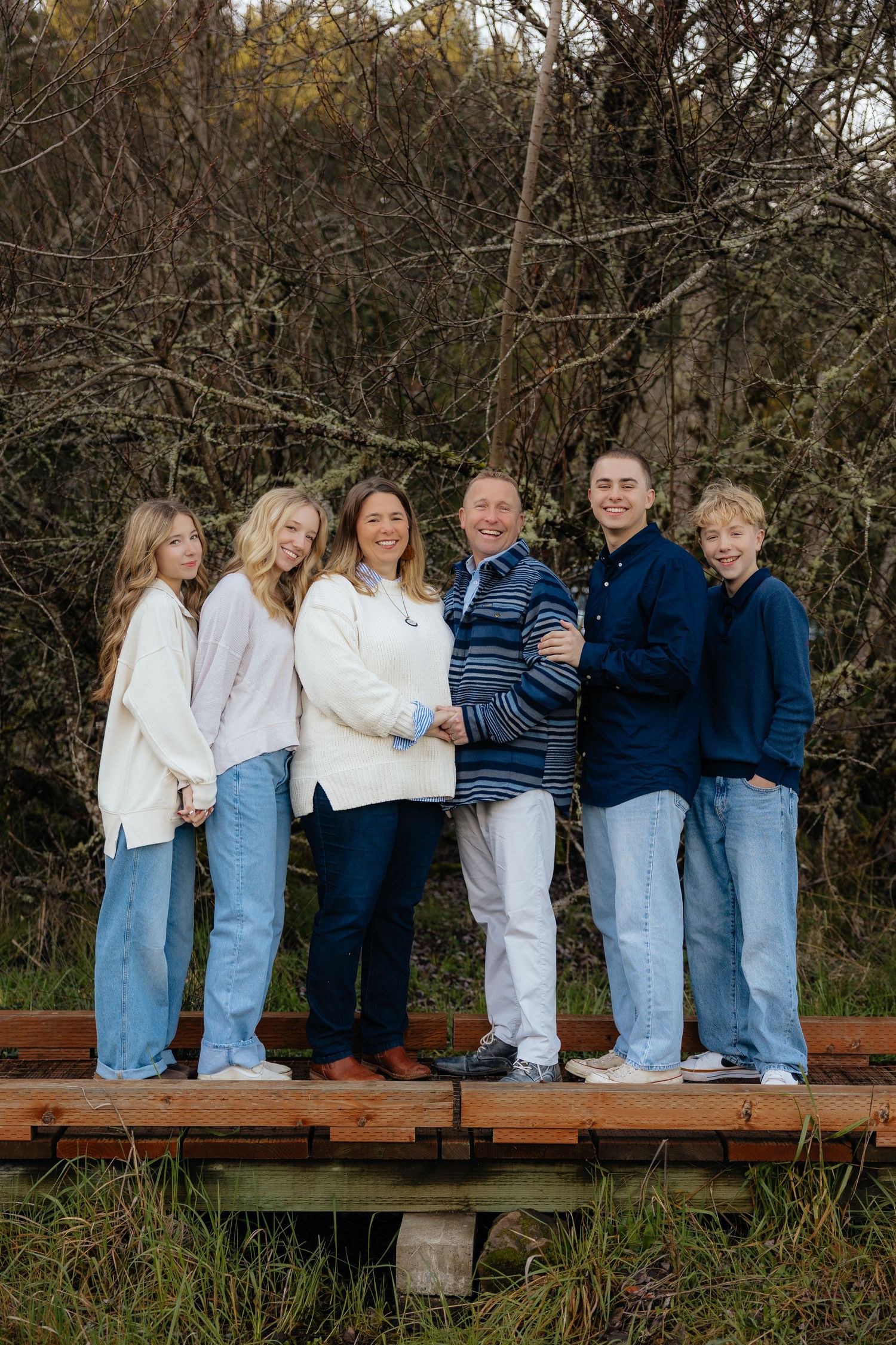 A series of candid outdoor family photos showing people sitting on a wooden bench in matching blue jeans and white shirts.