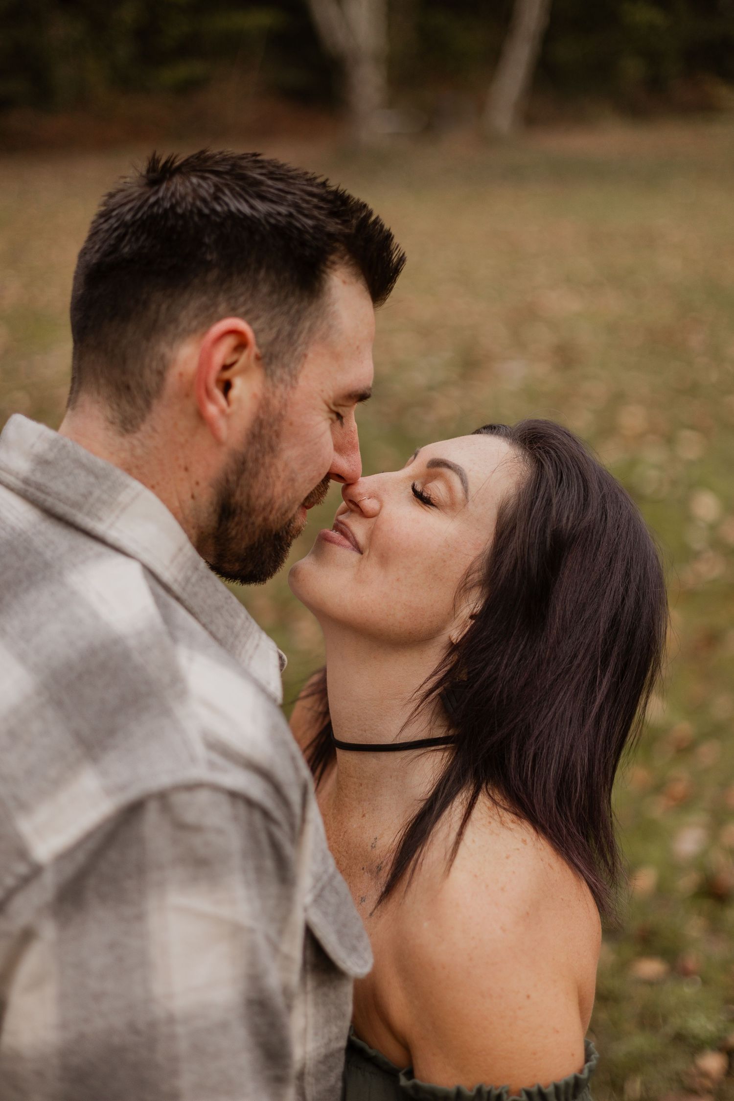 Intimate autumn engagement photos showing couple sharing tender kisses in natural lighting.