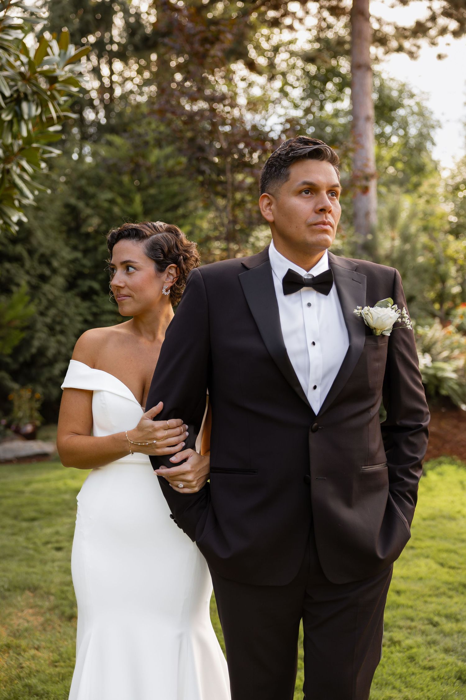 A couple in formal wedding attire share a playful moment outdoors during their wedding photoshoot.