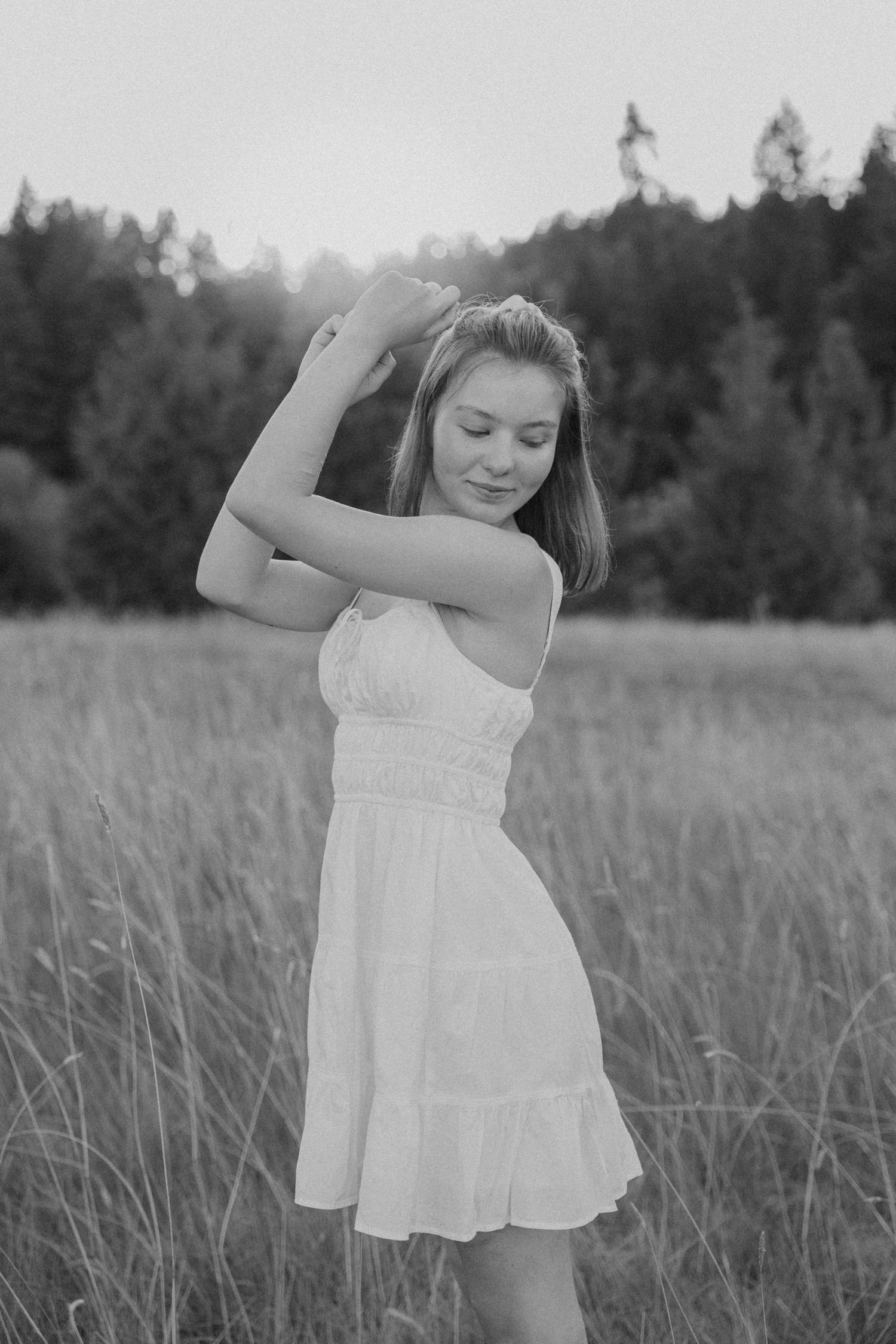 A dreamy black and white photo sequence shows someone in a white sundress dancing gracefully in a summer meadow.