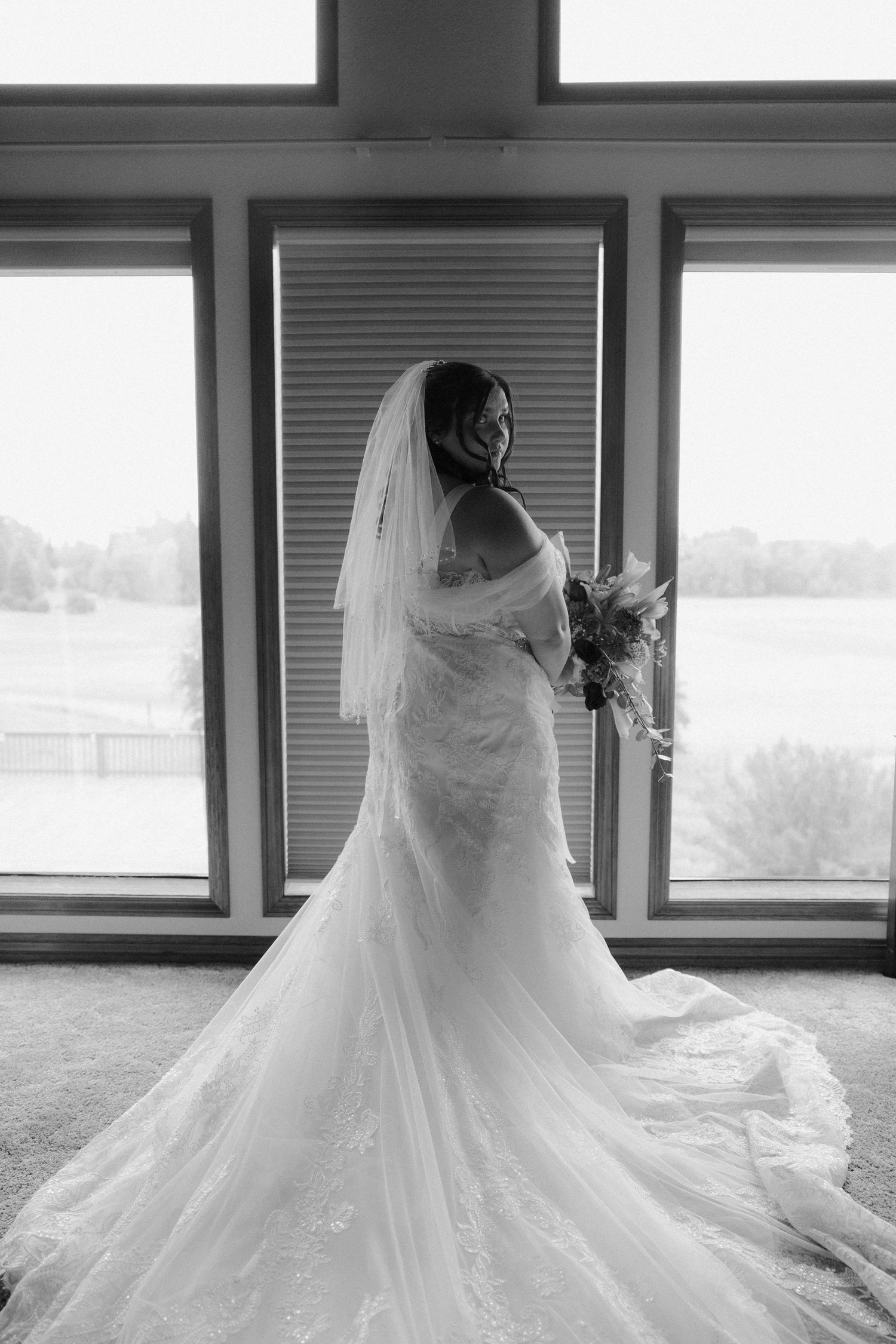 Wedding dress silhouette against window in black and white photography.