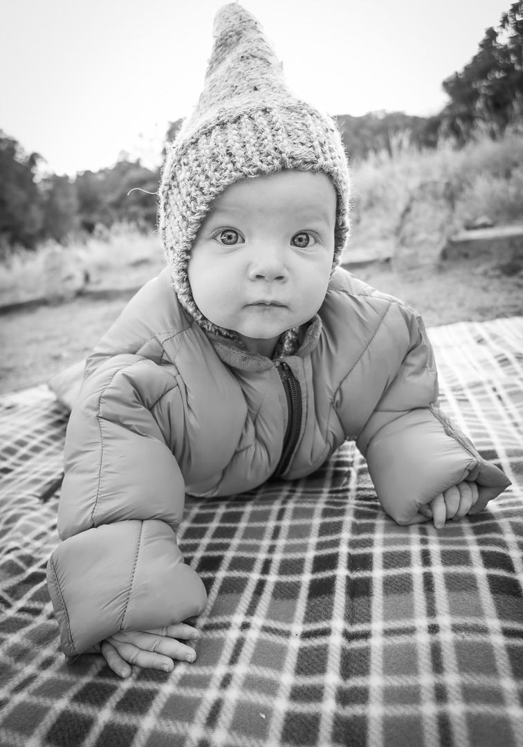 Black and white photo showing a baby wearing a knit hat and puffy infant sleeping bag camping at Great Sand Dunes National Park