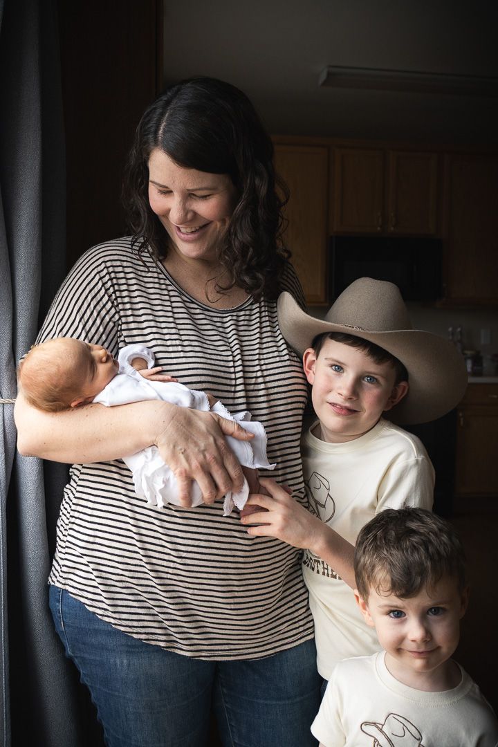 A mother and children hold their newborn baby.