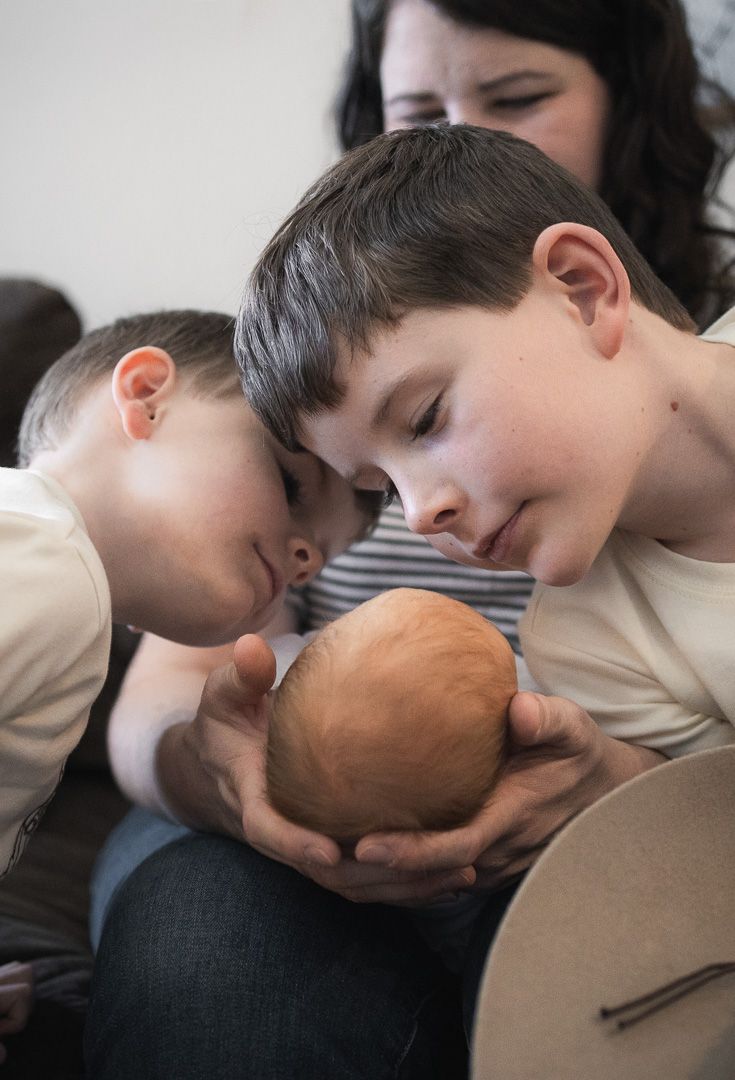 A series of intimate photos showing a young child bonding with a newborn sibling.
