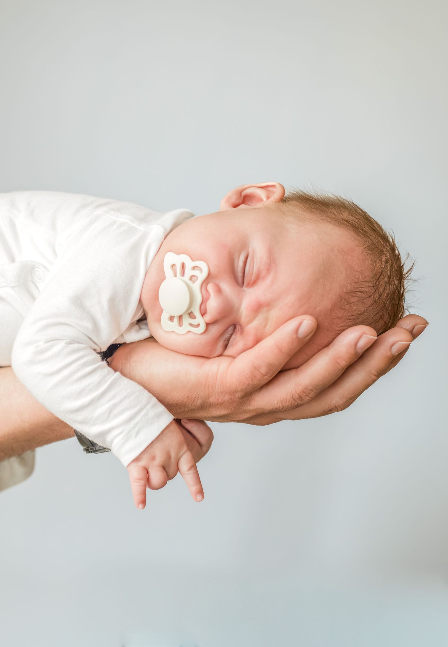 Pasgeboren baby met speen slapend op de hand van papa in Zuid-Holland.