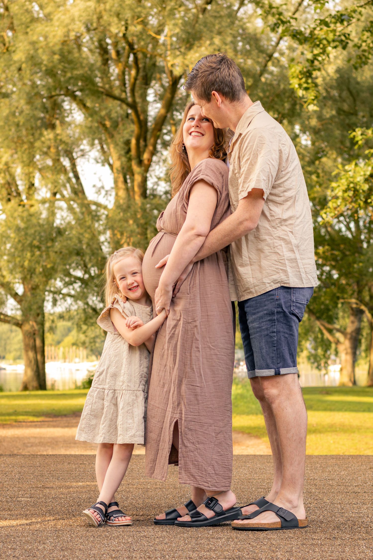 Gezin samen knuffelend in een bosgebied tijdens een zwangerschapsshoot in Zuid-Holland.