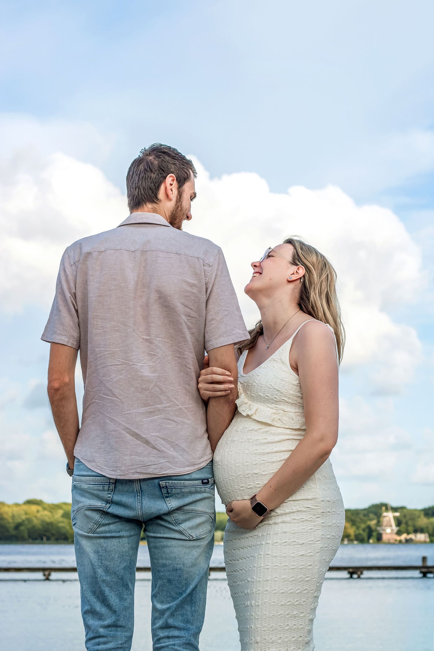 Mama to be die knuffelend en vol trots en liefde de papa aan kijkt tijdens een zwangerschapsshoot in Zuid-Holland.