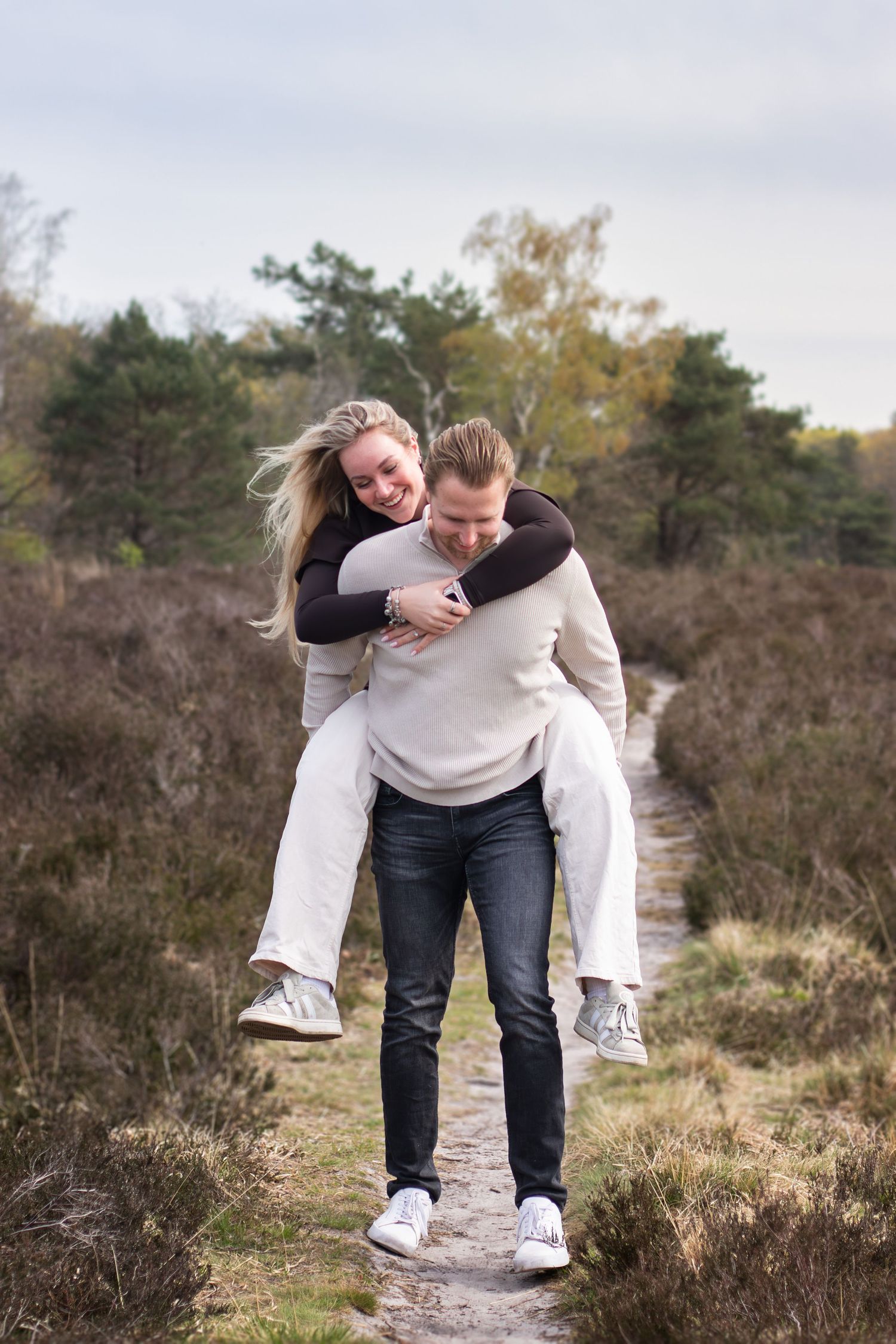 Verliefd stel waarbij vrouw op de rug zit en samen lachend in bosgebied in Breda.