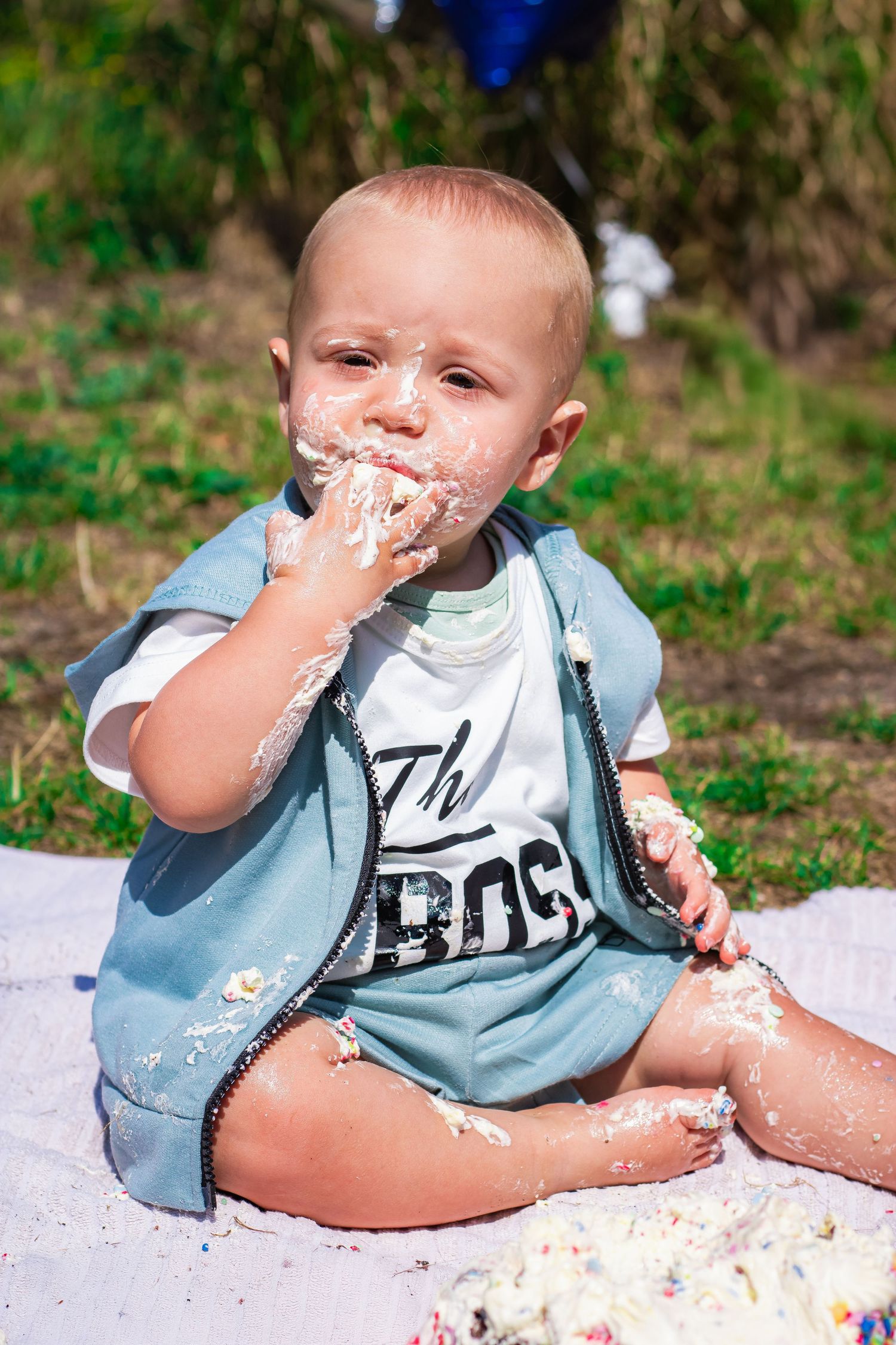 Baby met zijn hand vol taart in zijn mond tijdens een cakesmashshoot in Breda.