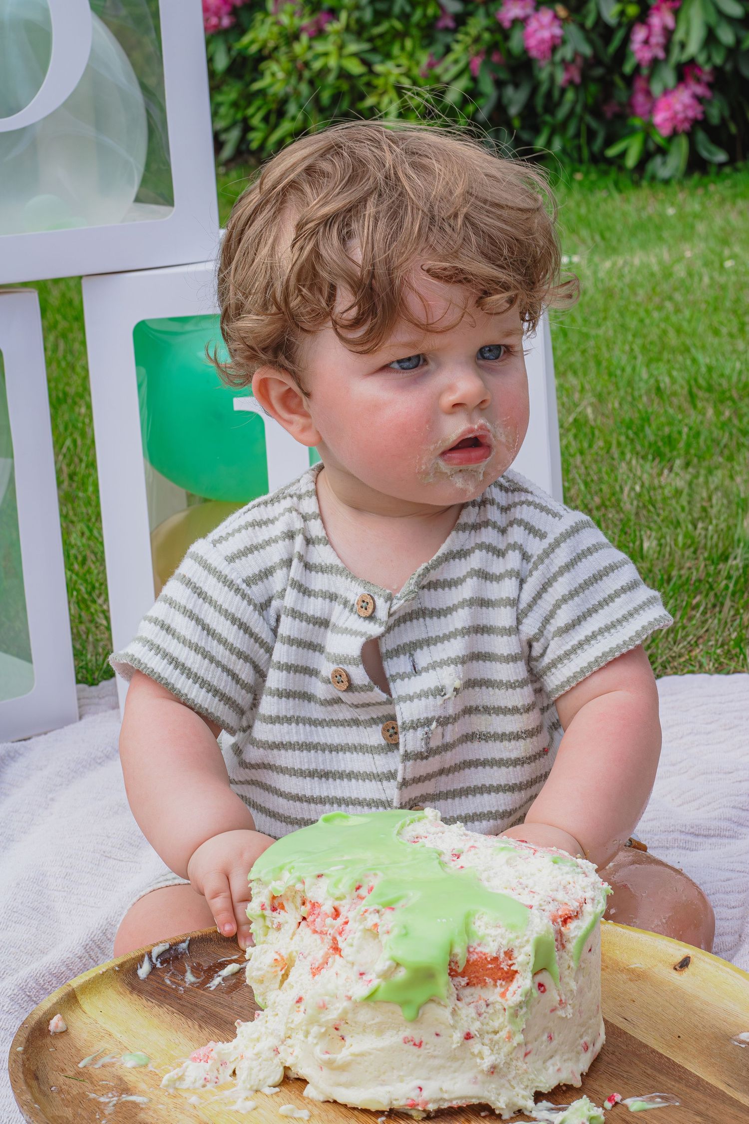 Baby die nieuwsgierig rondkijkt en rustig geniet van zijn taart tijdens een cakesmashshoot in Breda.