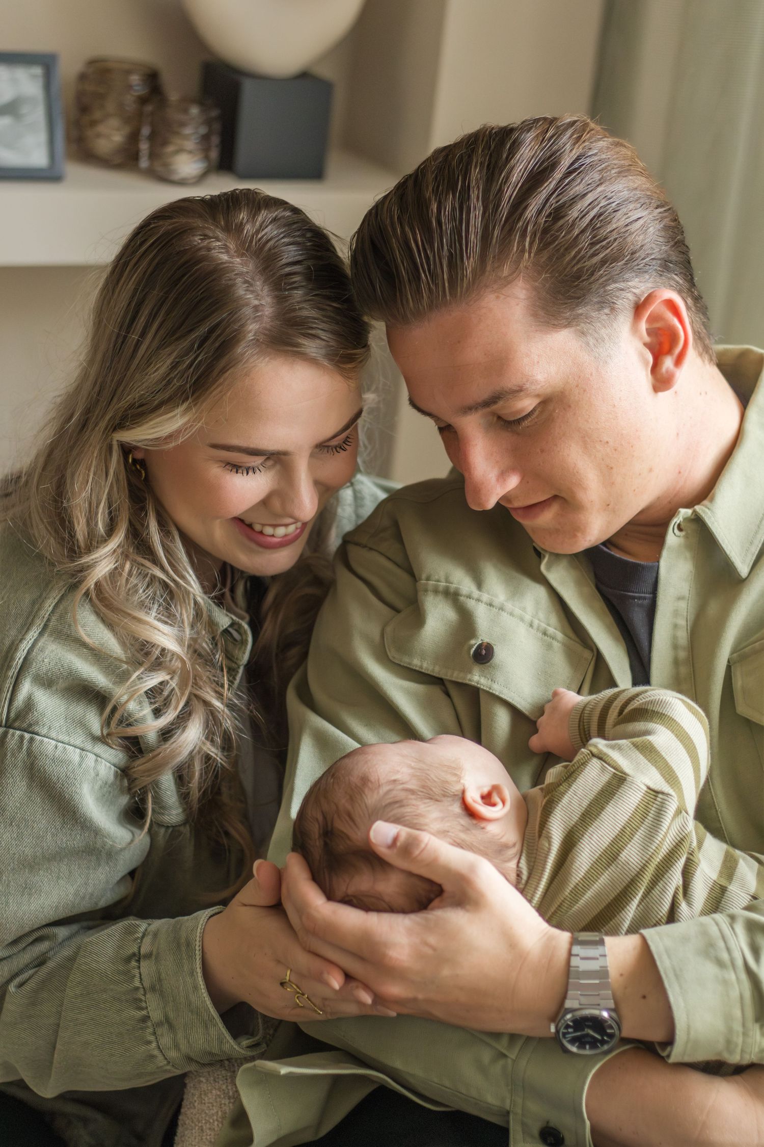 Papa en mama knuffelend met newborn tijdens een newbornshoot in Zuid-Holland.