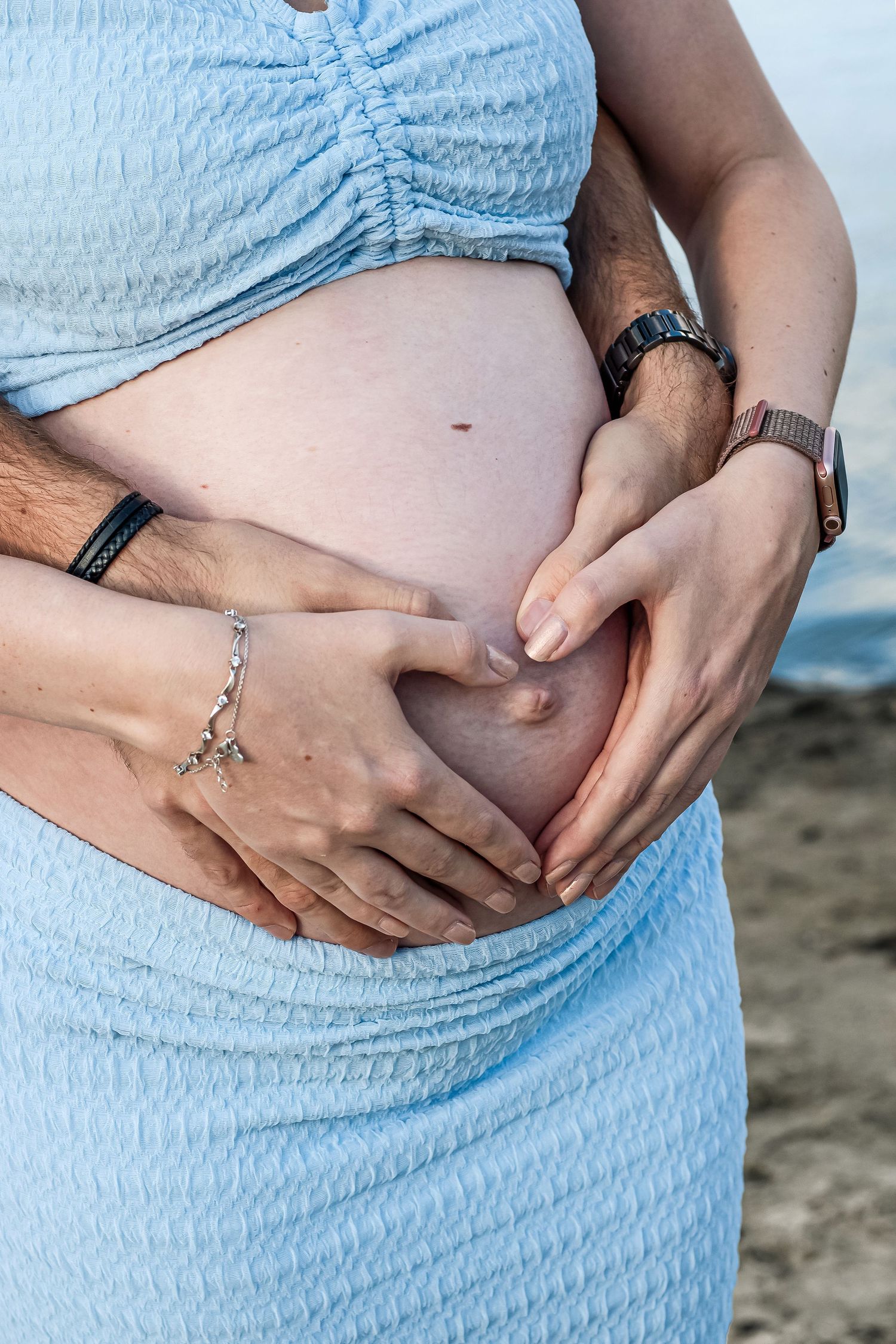 Twee handen liefdevol op de zwangerebuik tijdens een zwangerschapsshoot in Zuid-Holland.
