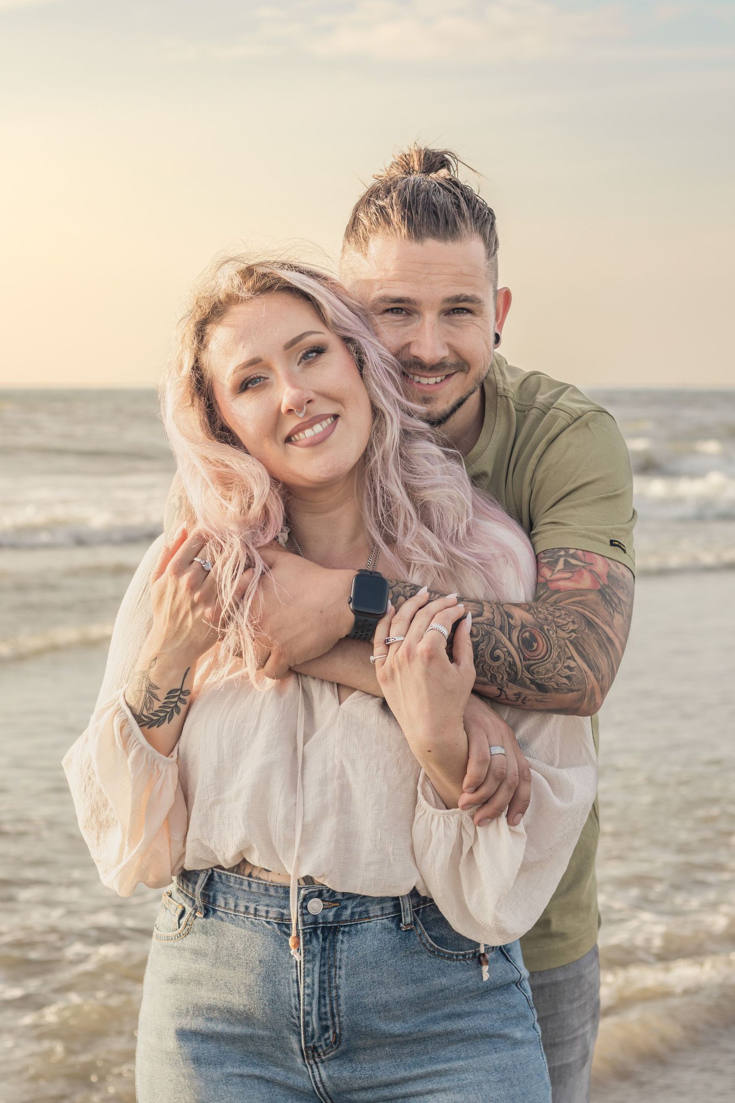 Koppel knuffelend op het strand met golden hour tijdens een loveshoot in Zuid-Holland.