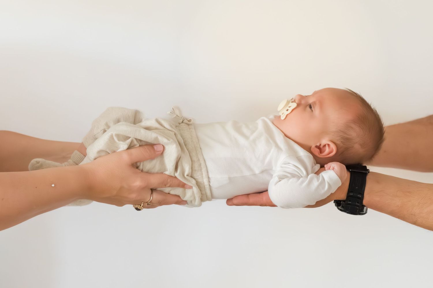 Baby slapend in handen van papa en mama tijdens een newbornshoot in Zuid-Holland.